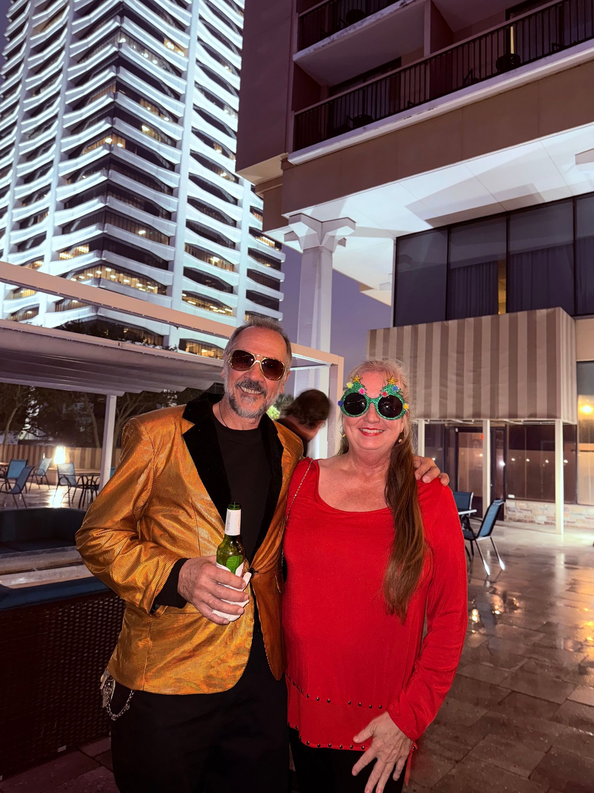 A man and a woman are posing for a picture in front of a building.