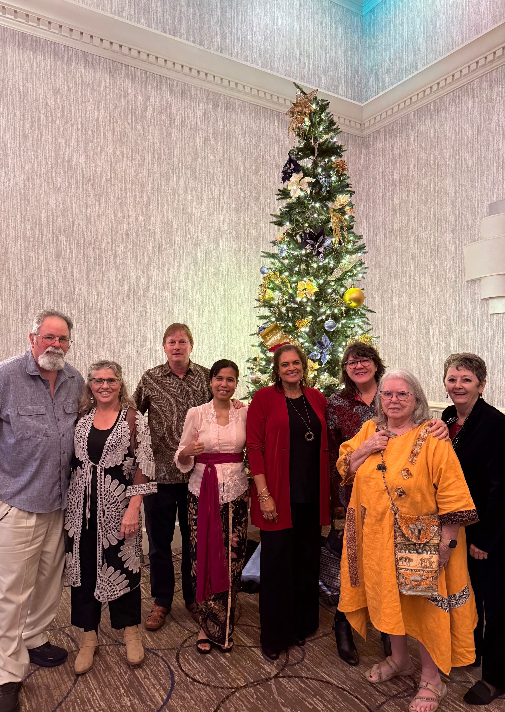 A group of people are posing for a picture in front of a christmas tree.