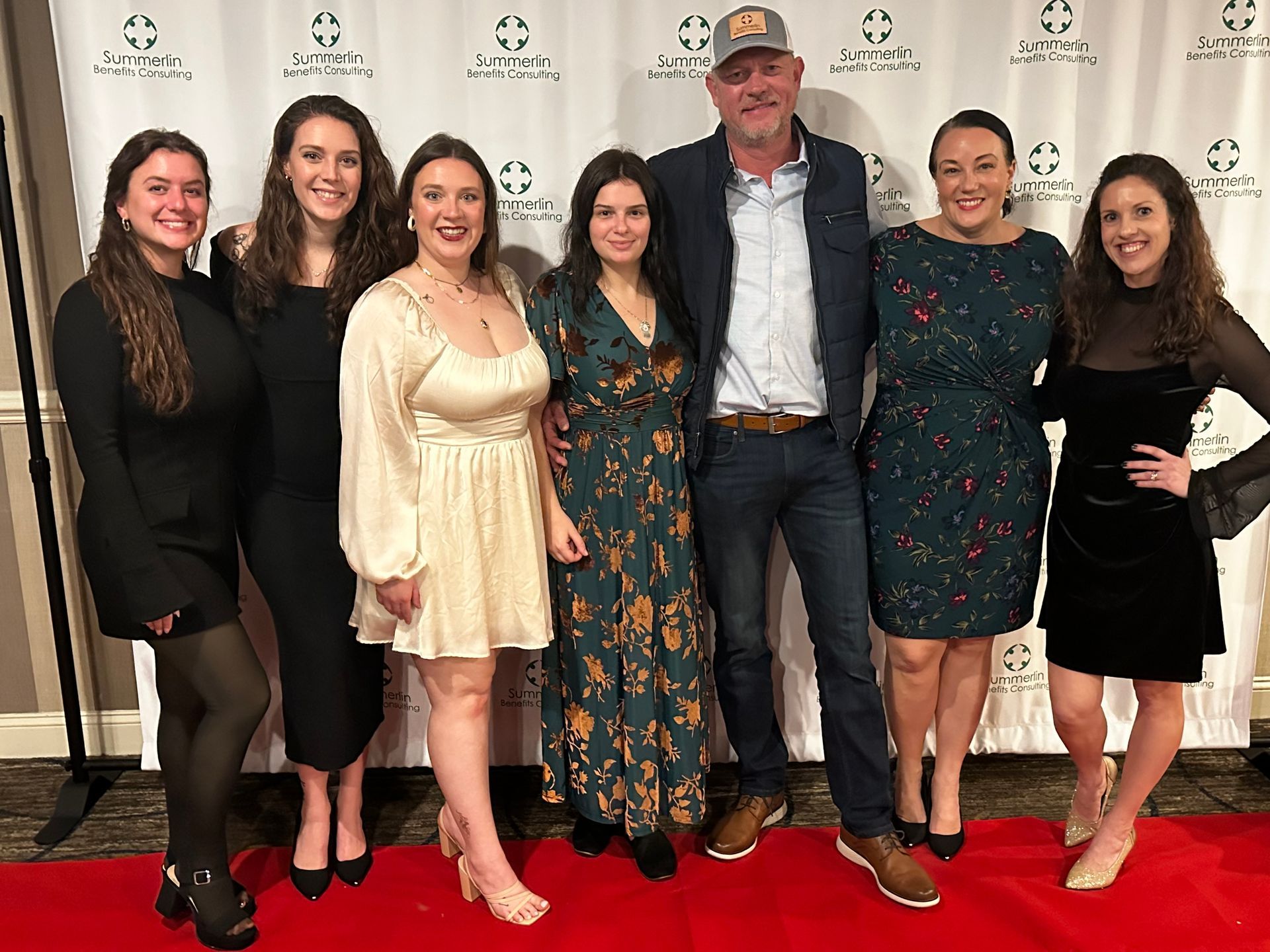 A group of people are posing for a picture on a red carpet.
