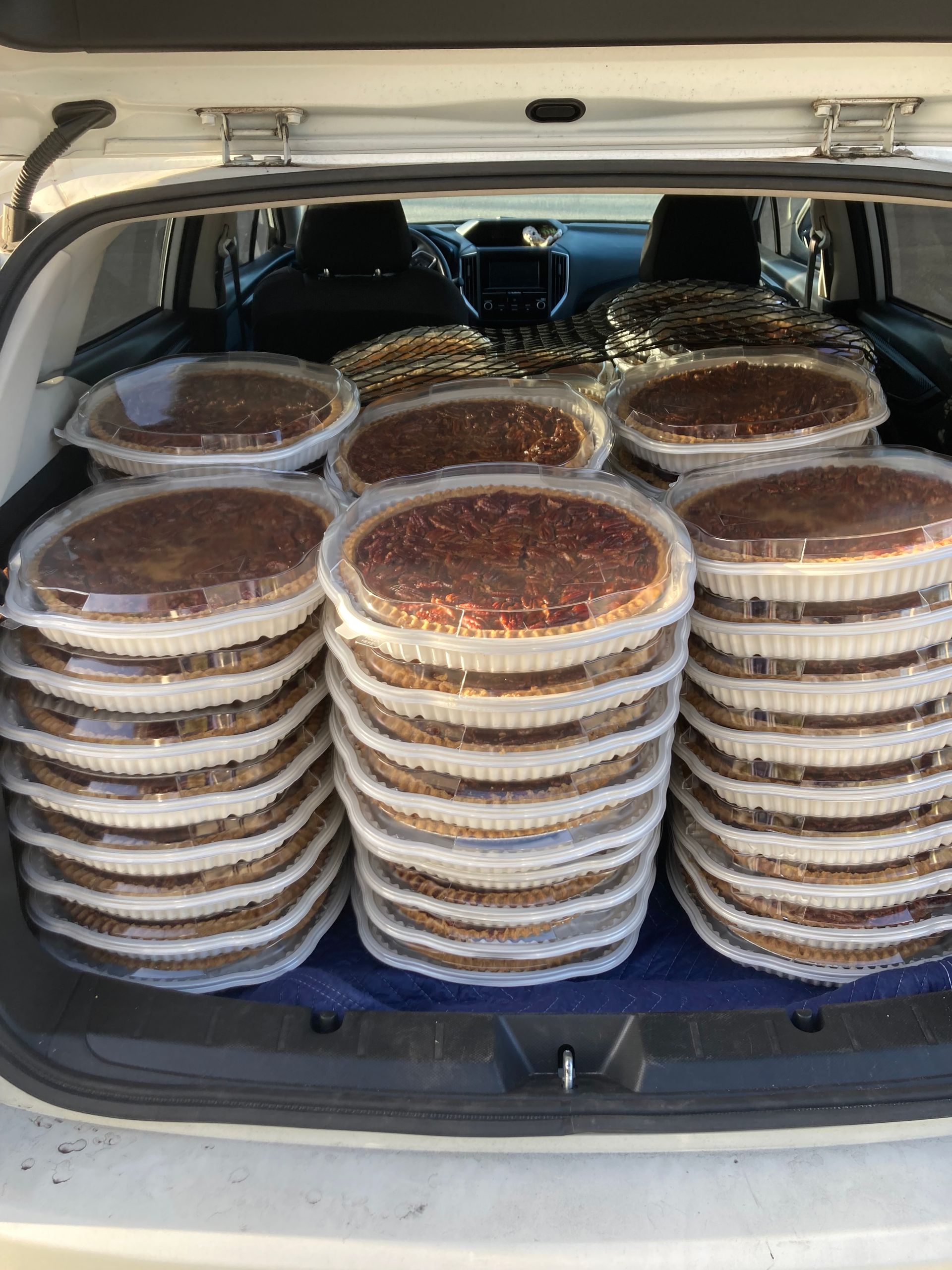A stack of pecan pies in the back of a car.
