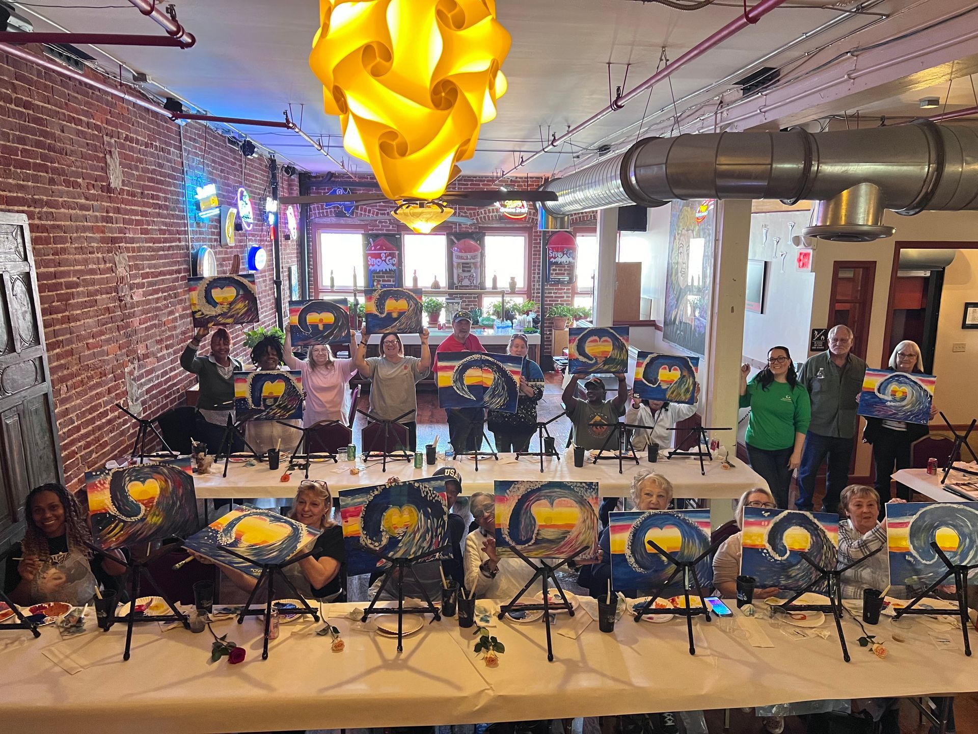 A group of people are standing around a table with paintings on it.
