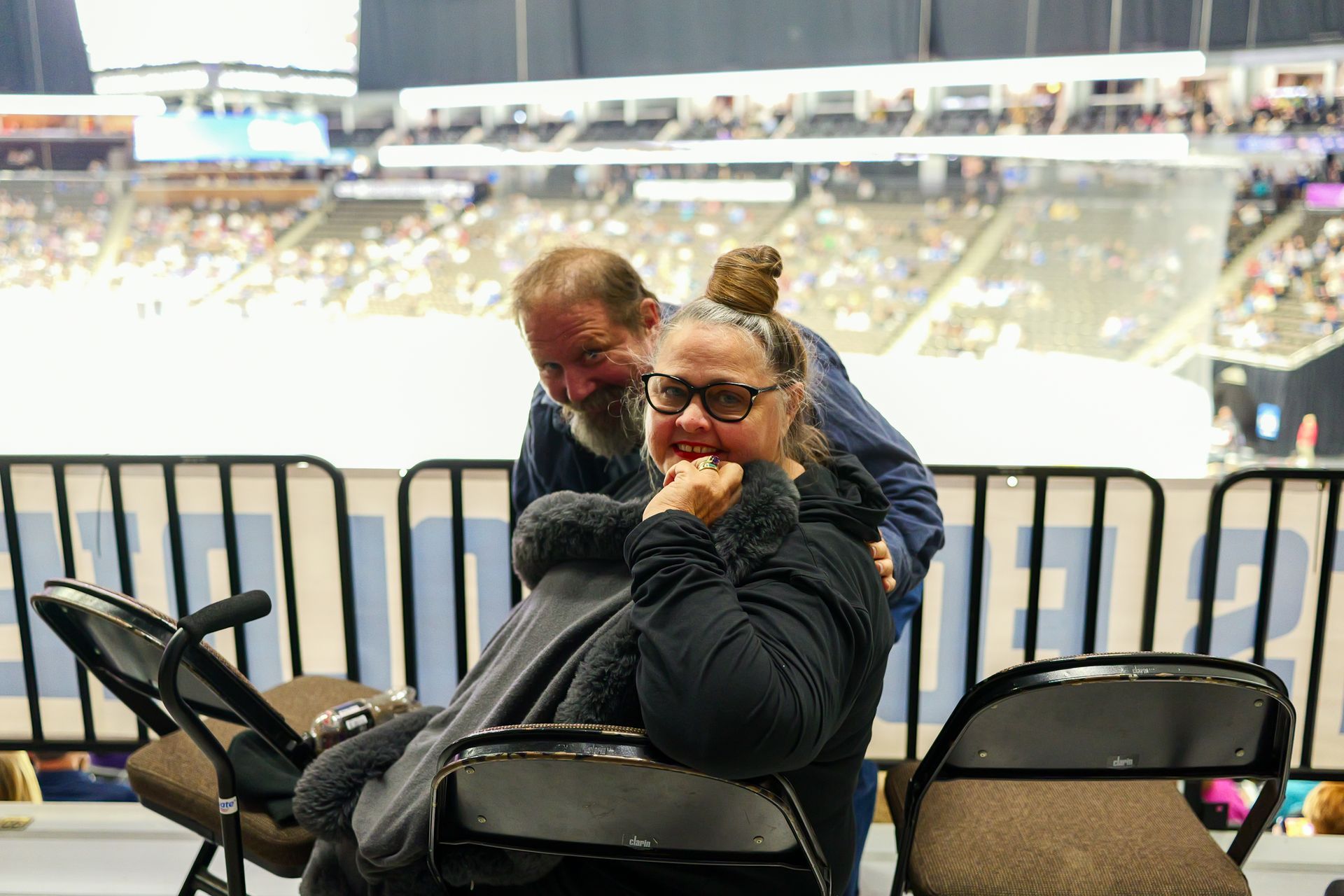 A woman in a wheelchair is sitting next to a man in a stadium.