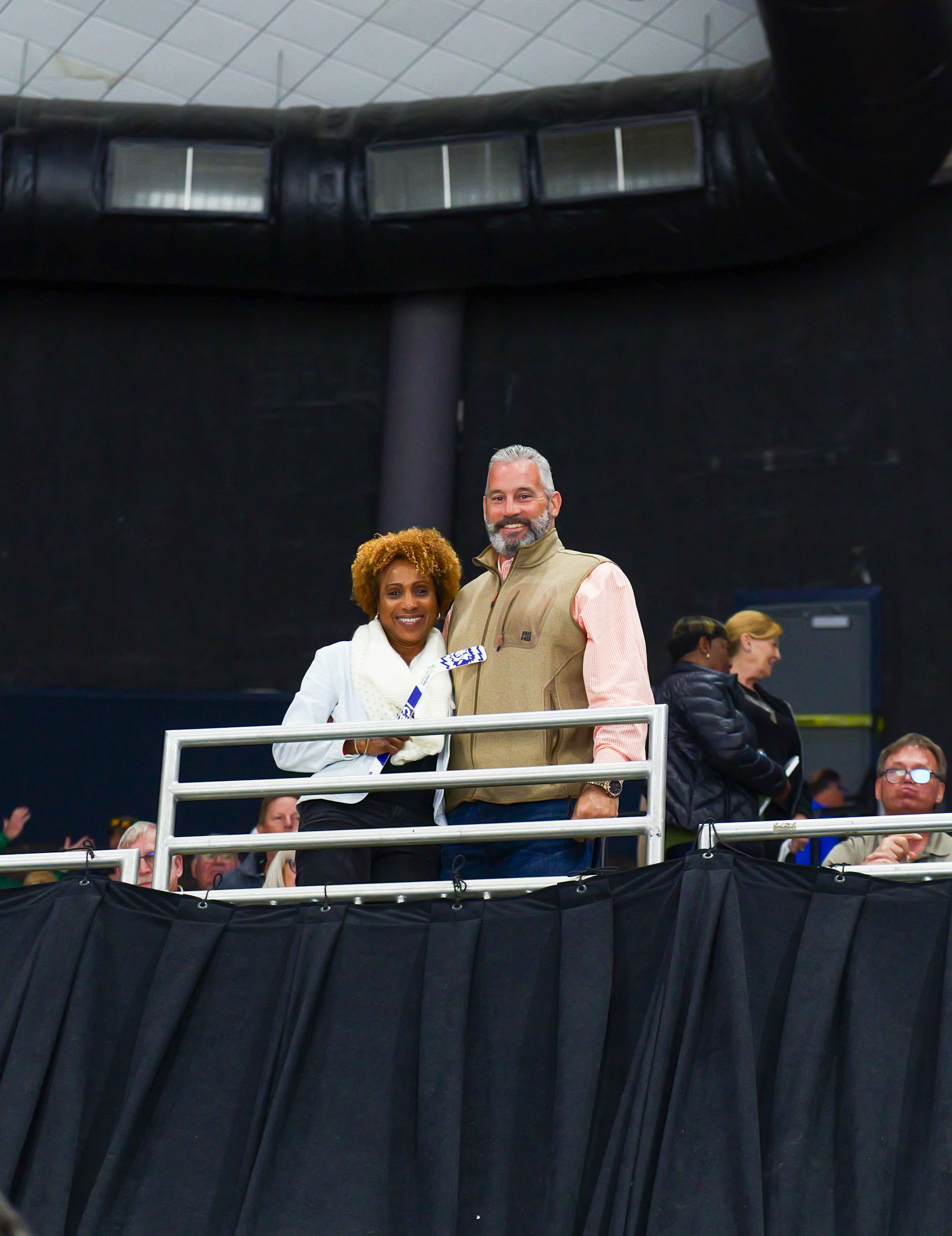 A man and a woman are standing on a stage in front of a crowd