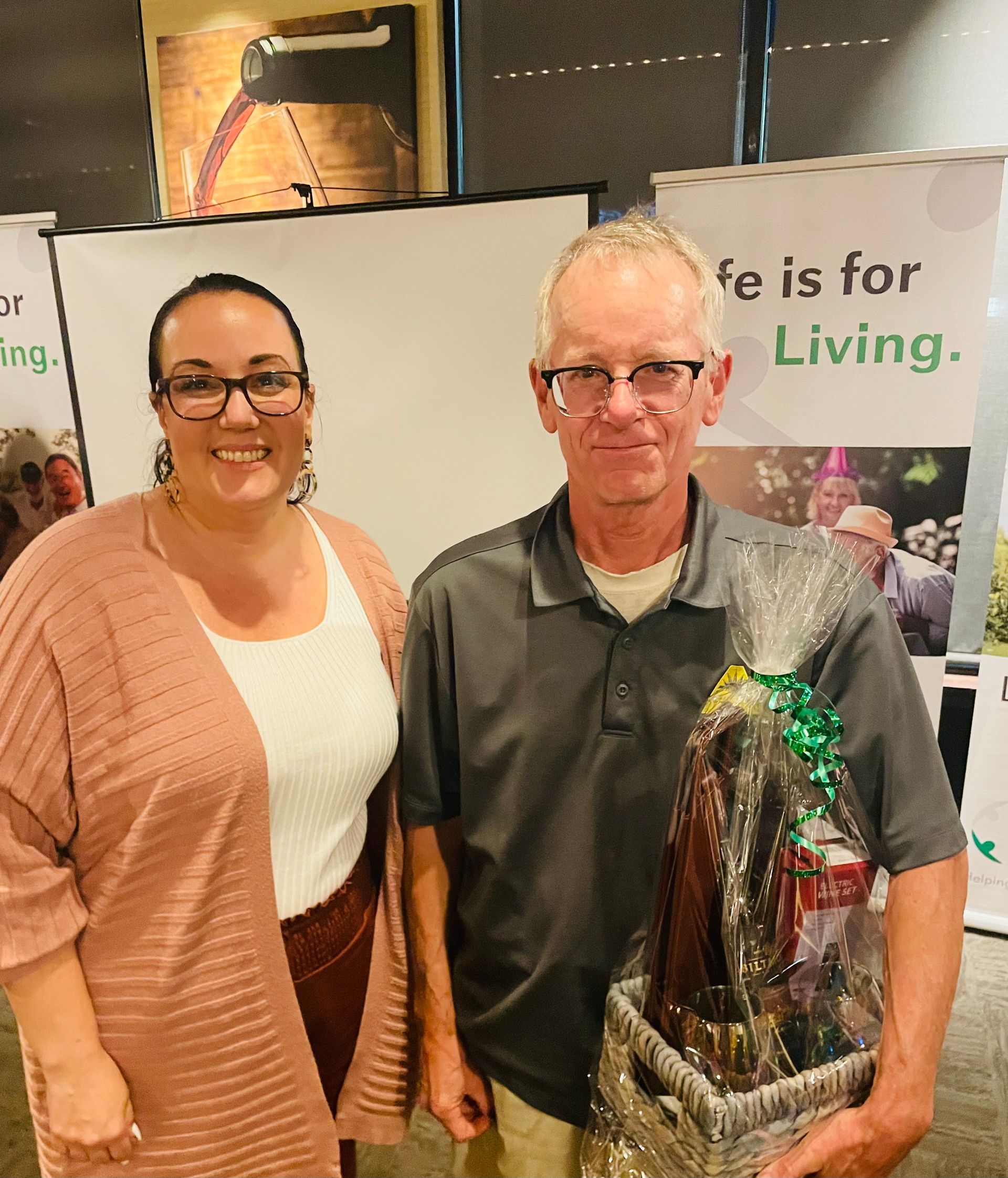 A man and a woman are posing for a picture in front of a sign that says 