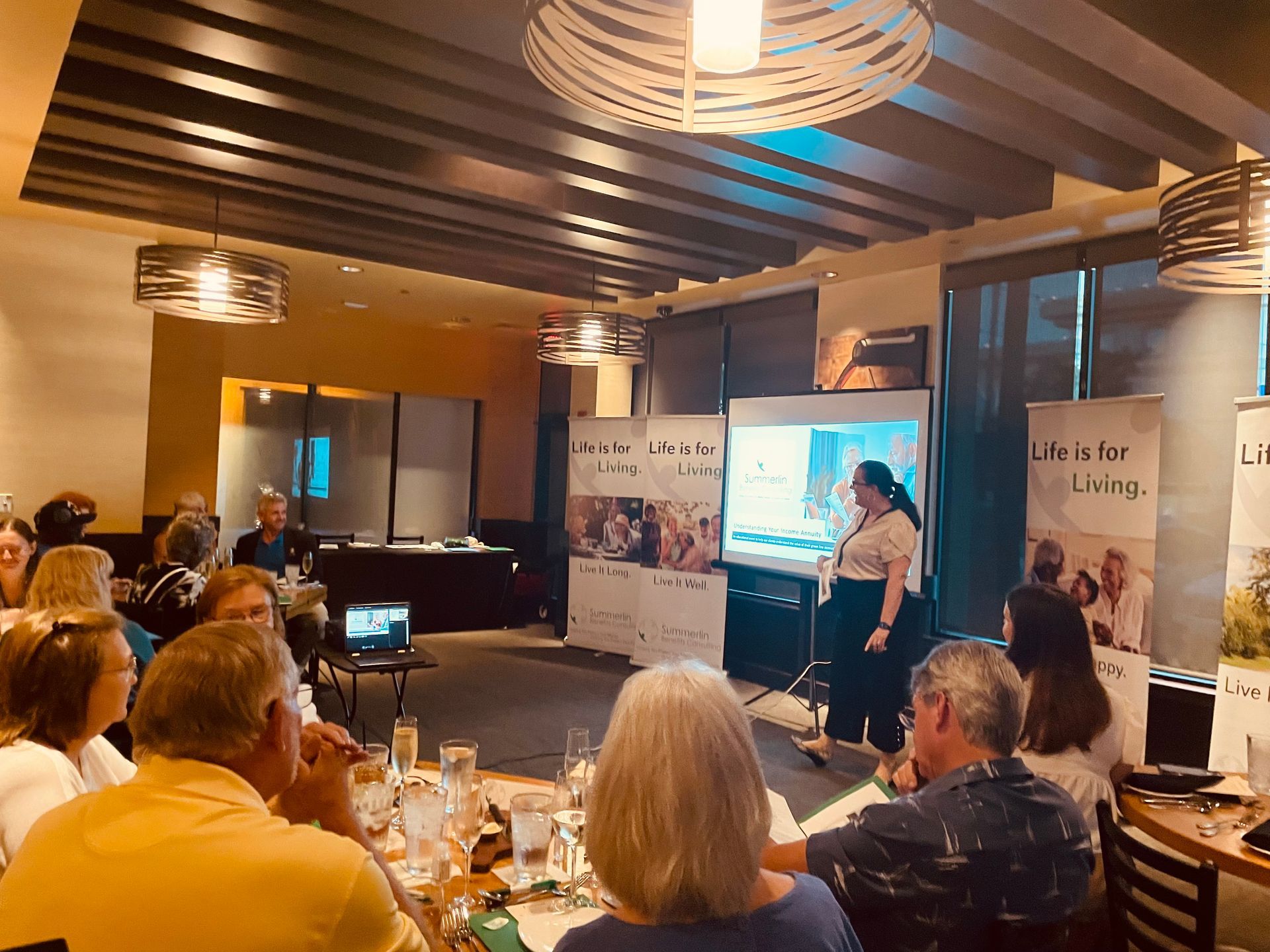 A woman is giving a presentation to a group of people in a restaurant.