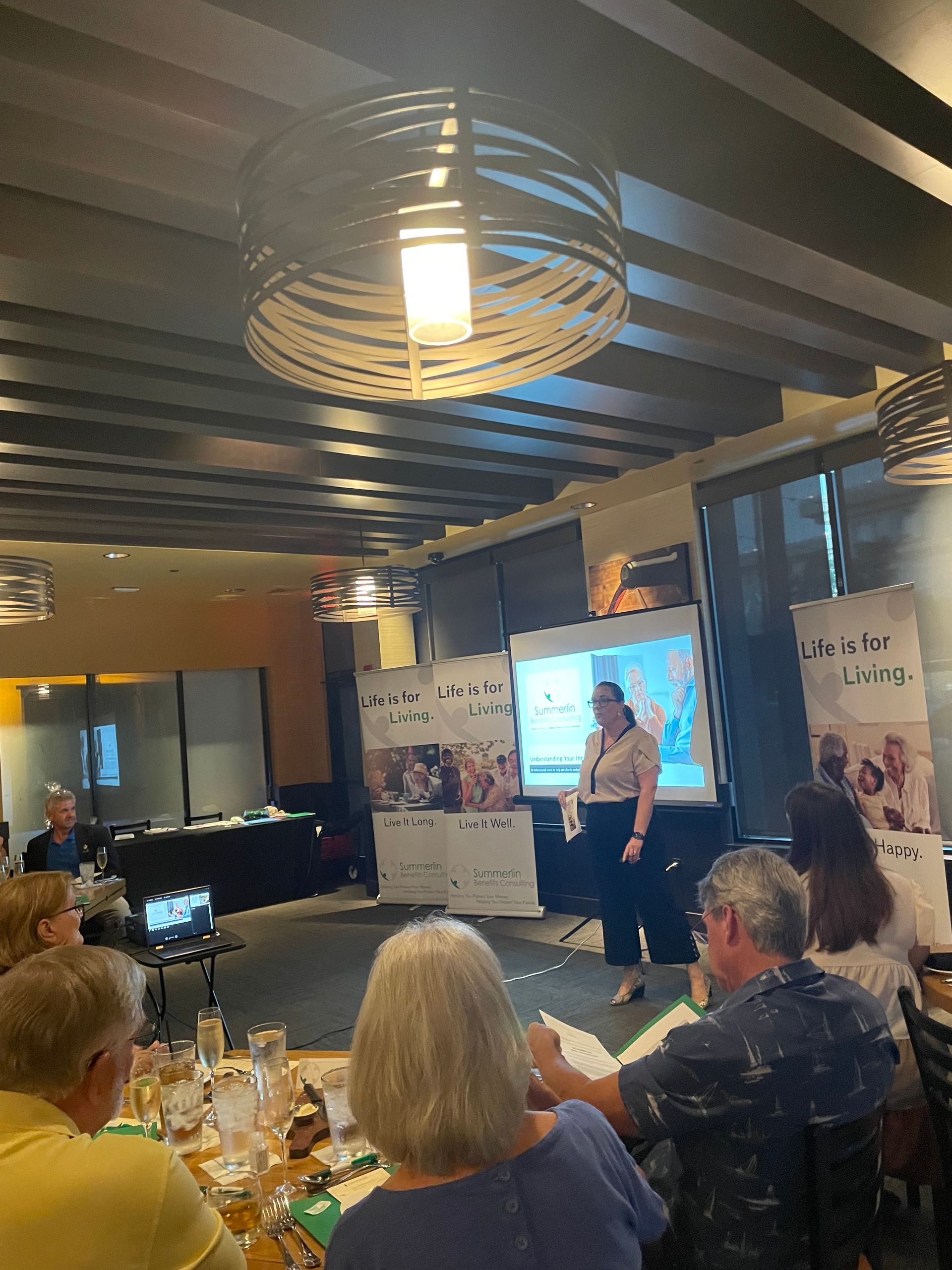 A group of people are sitting at a table watching a presentation.