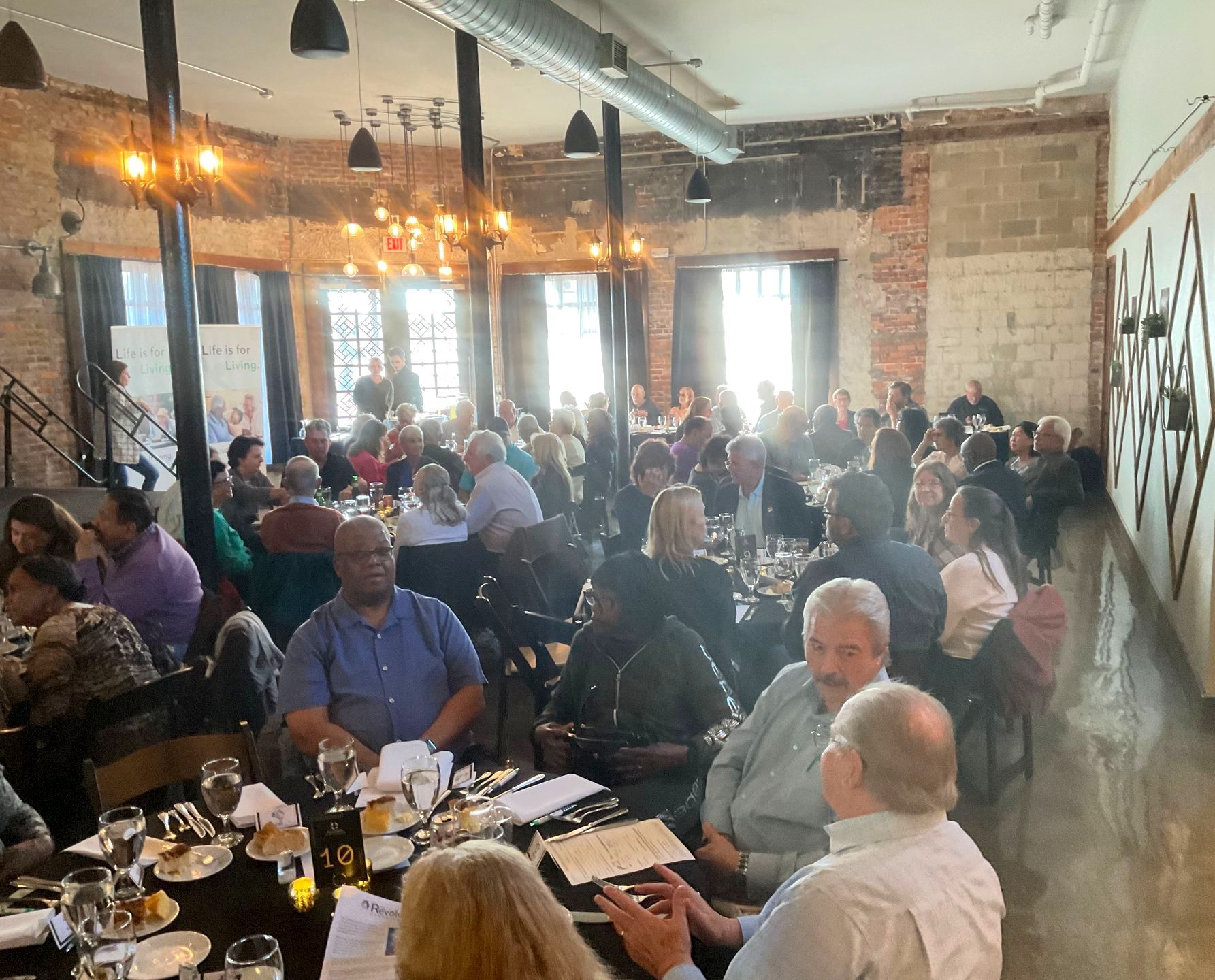 A large group of people are sitting at tables in a restaurant.