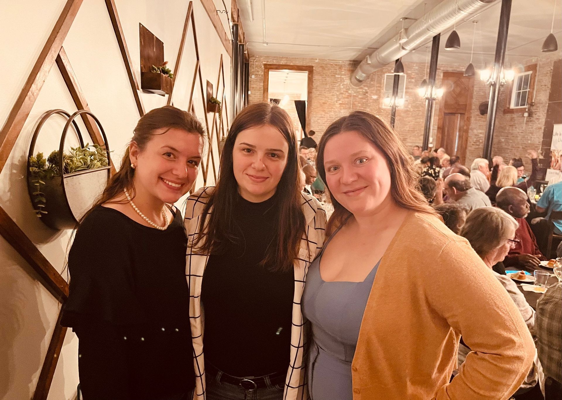 Three women are posing for a picture in a restaurant.