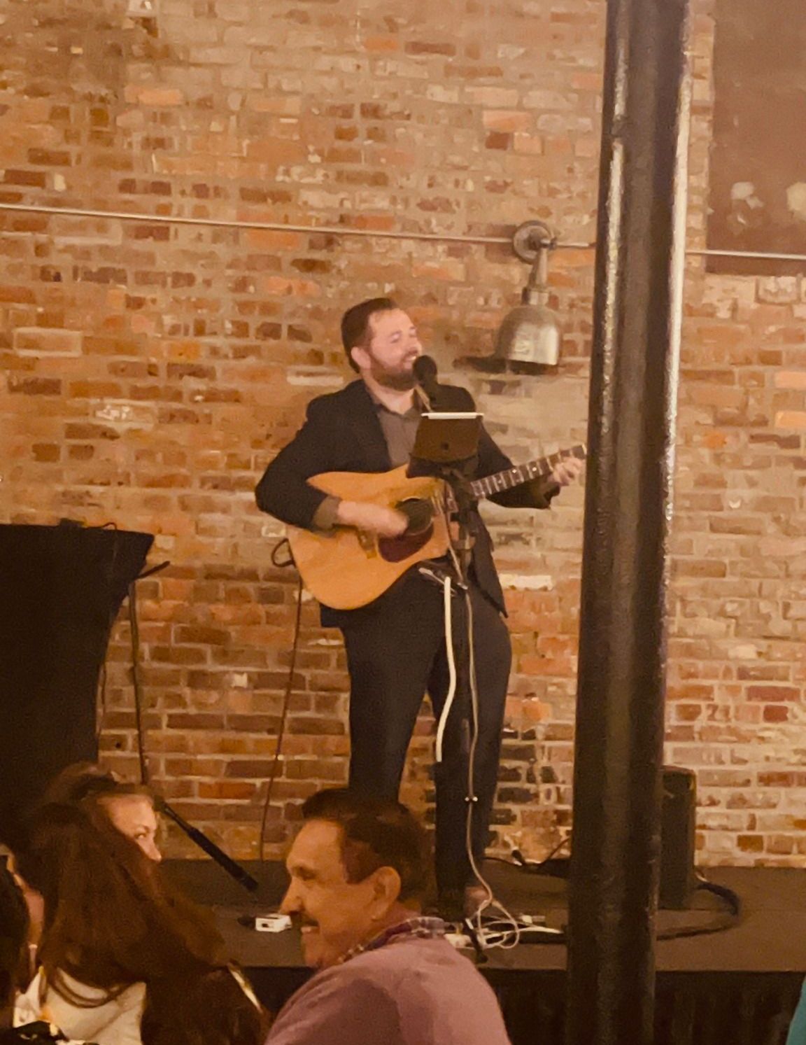 A man is singing into a microphone while playing a guitar.