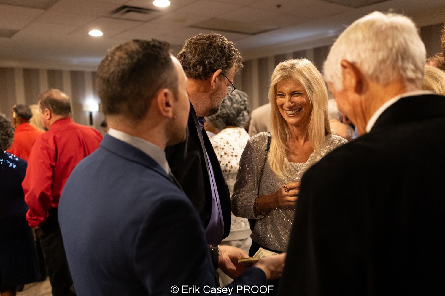 A group of people are standing in a room talking to each other.