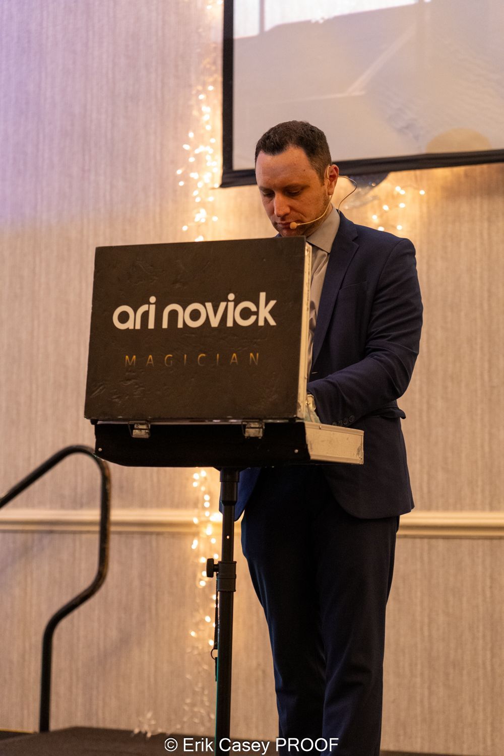 A man in a suit is standing in front of a sign that says ari novick