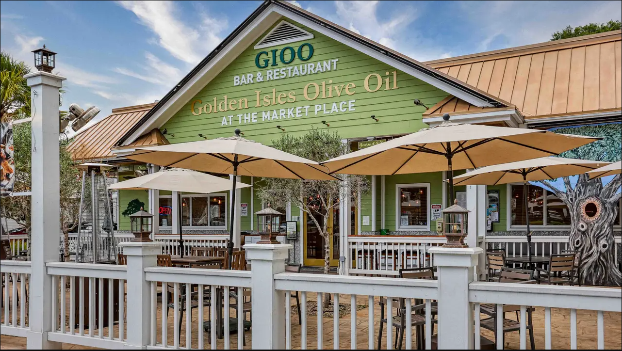 A restaurant with umbrellas and tables in front of it.
