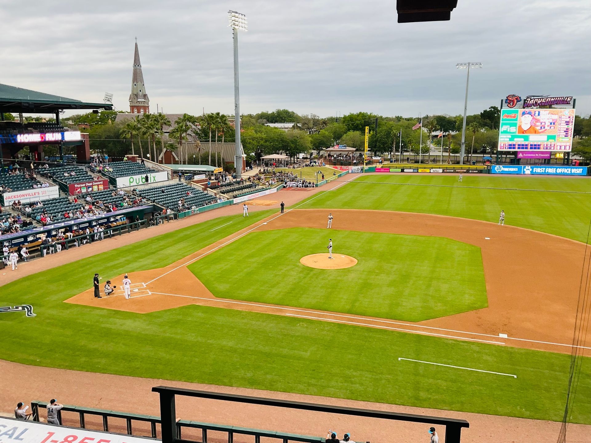 A baseball field with a large screen in the background.