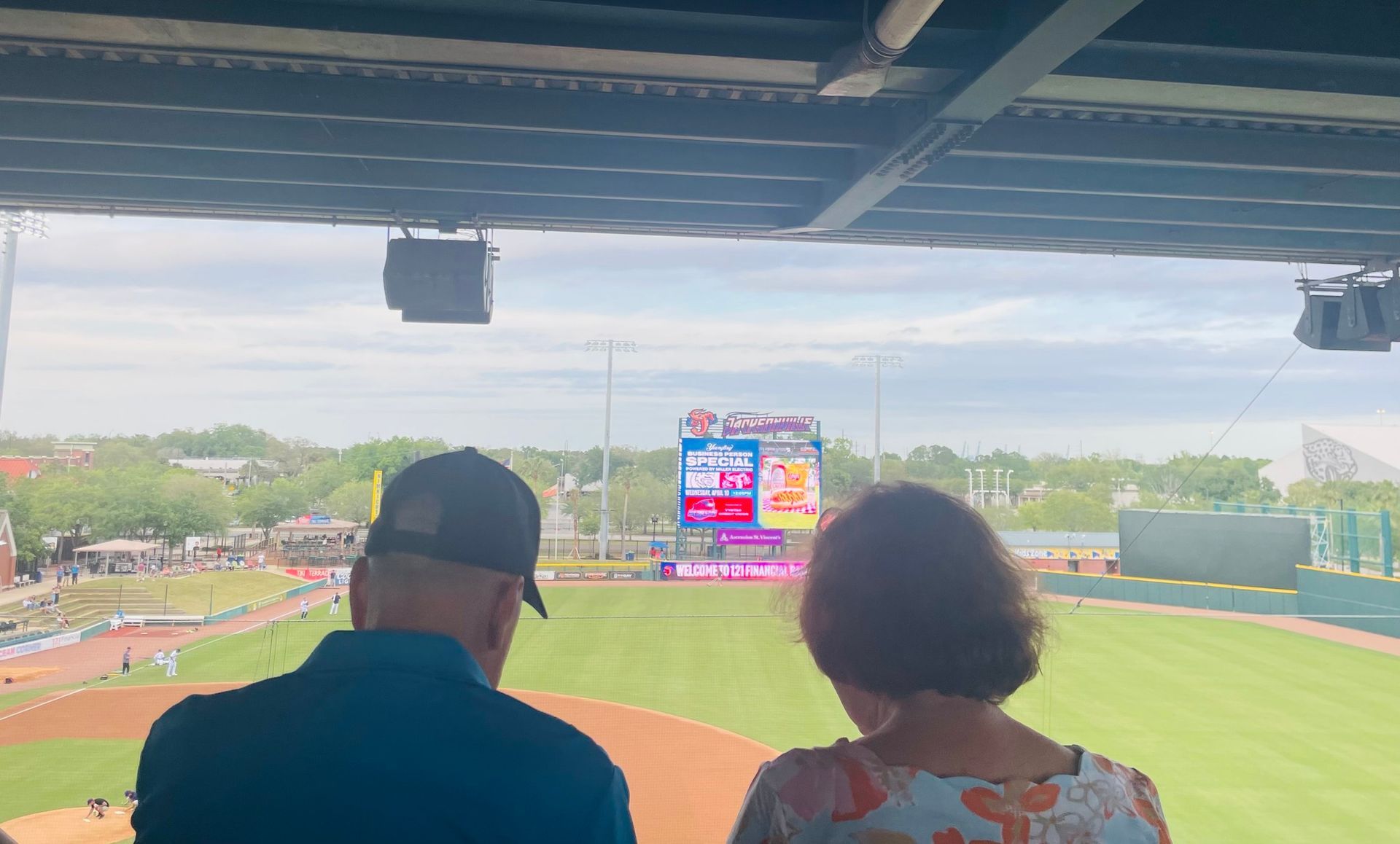 A man and a woman are sitting in a stadium watching a baseball game.