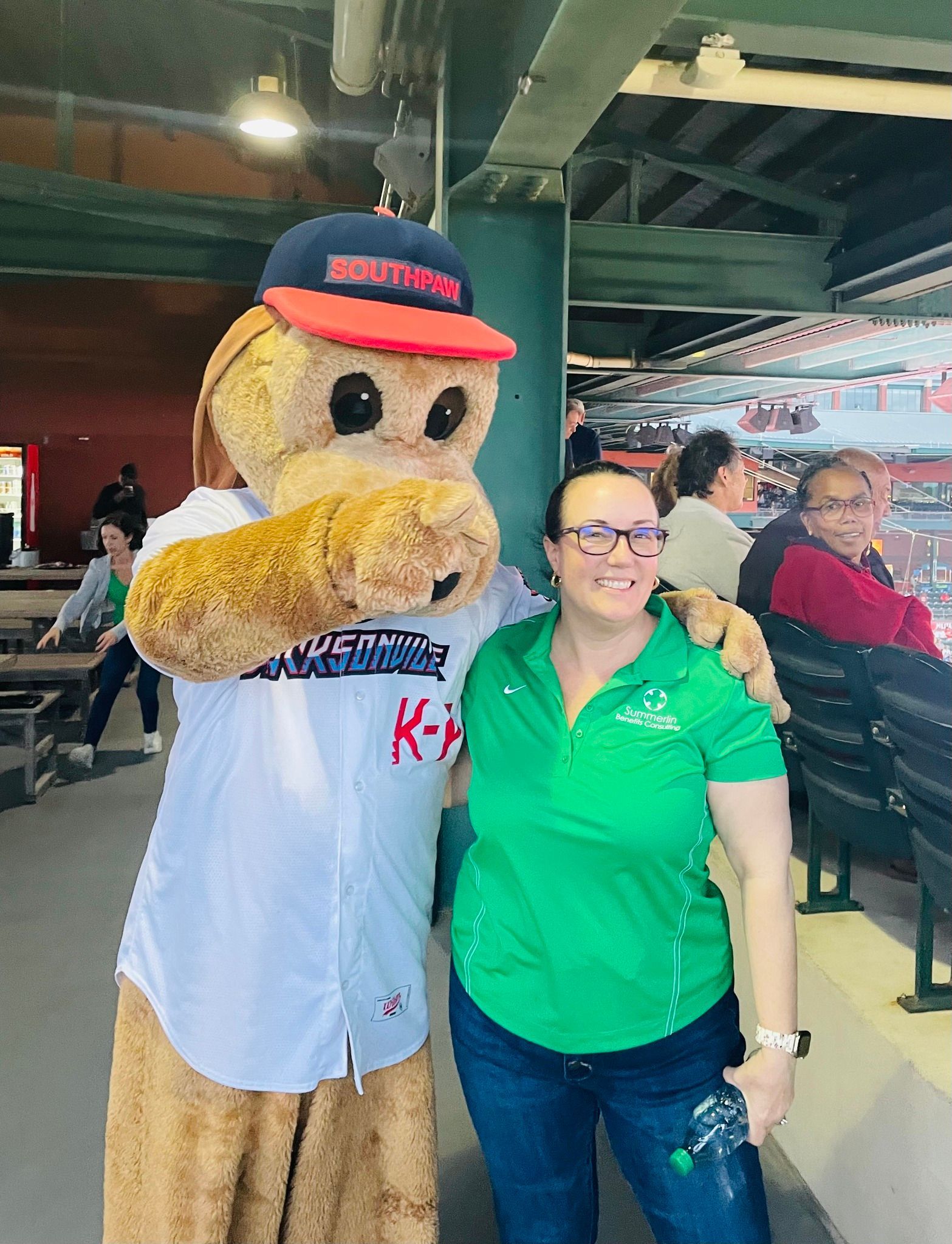 A woman is standing next to a mascot at a baseball game.
