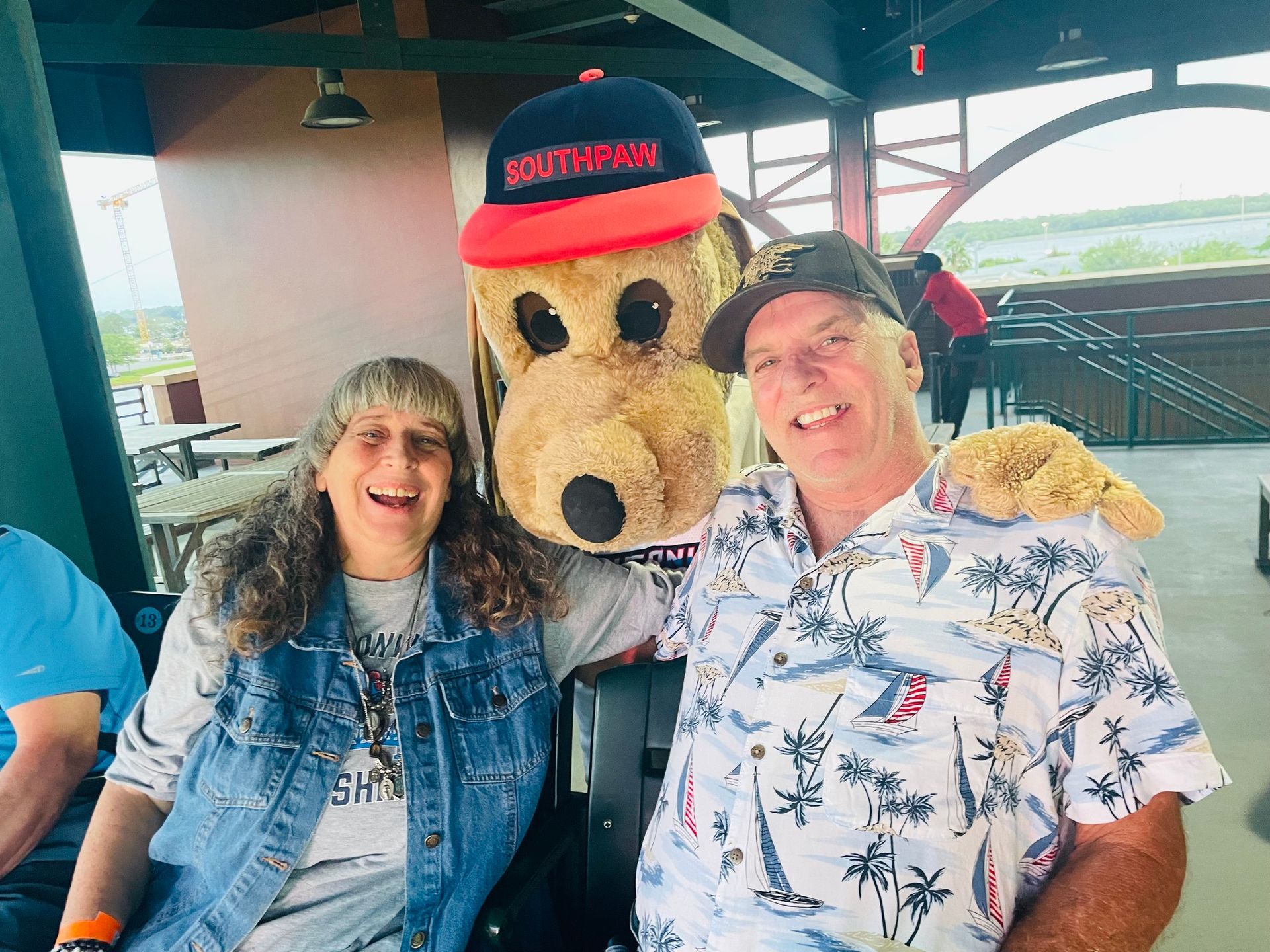 A man and a woman are posing for a picture with a stuffed dog.