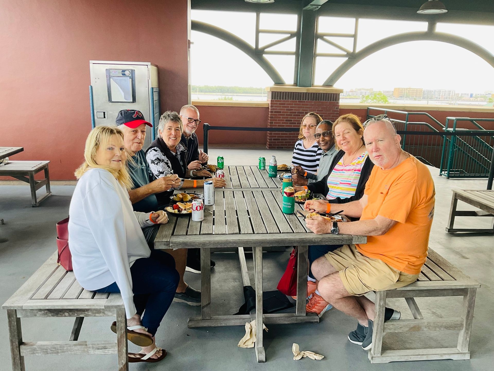 A group of people are sitting at a picnic table eating food.
