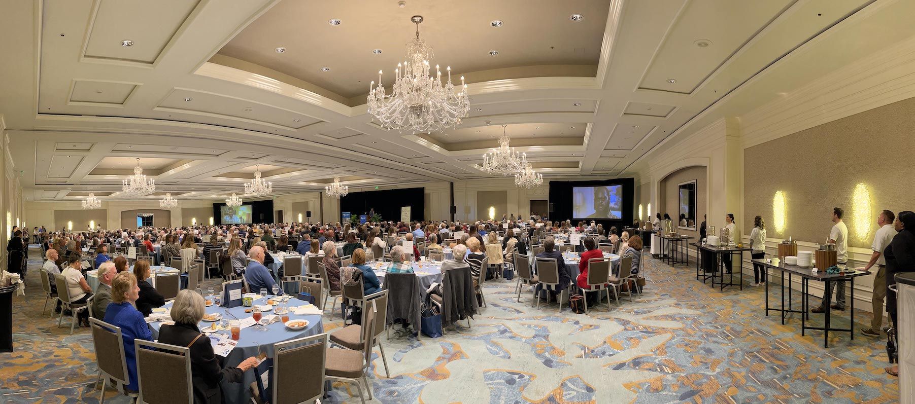 A large room filled with people sitting at tables and chairs.