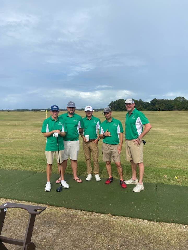 A group of men are posing for a picture on a golf course.