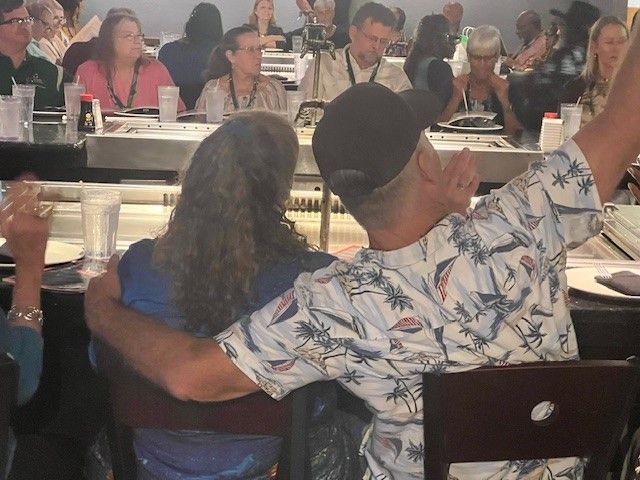 A man and woman are hugging each other while sitting at a table in a restaurant