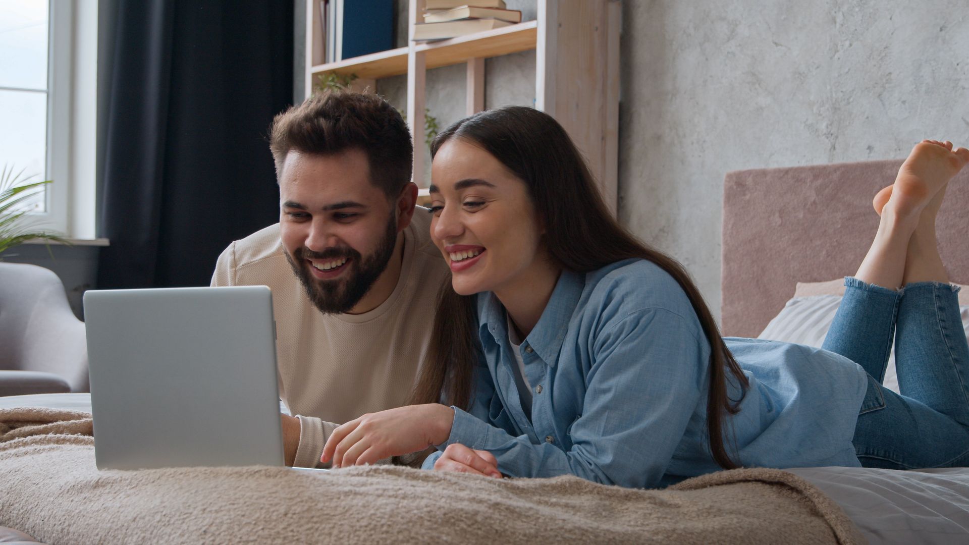 Happy couple looking at computer on the couch.