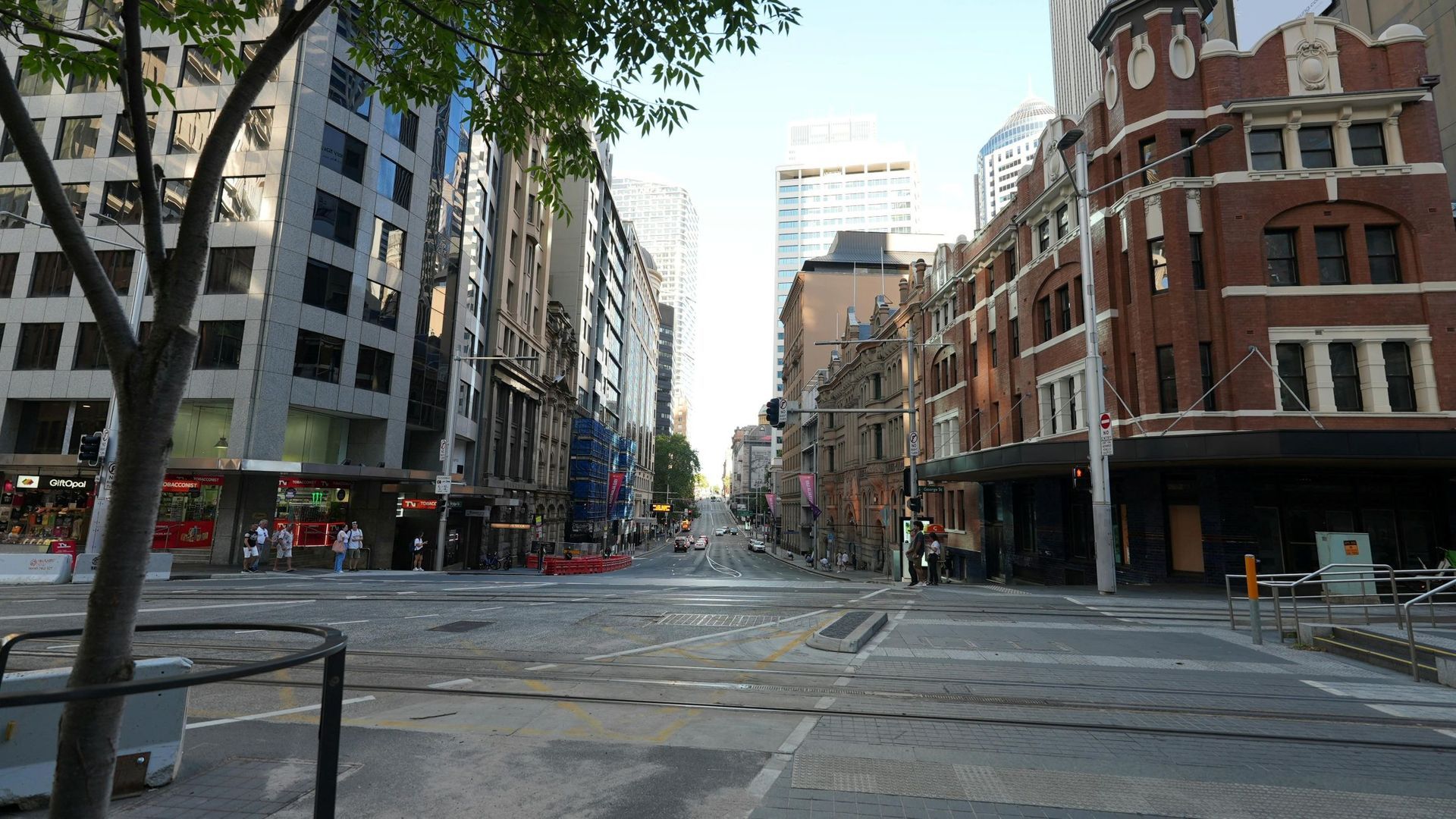 Wide view of a quiet city intersection lined with modern office buildings and a historic red-brick c