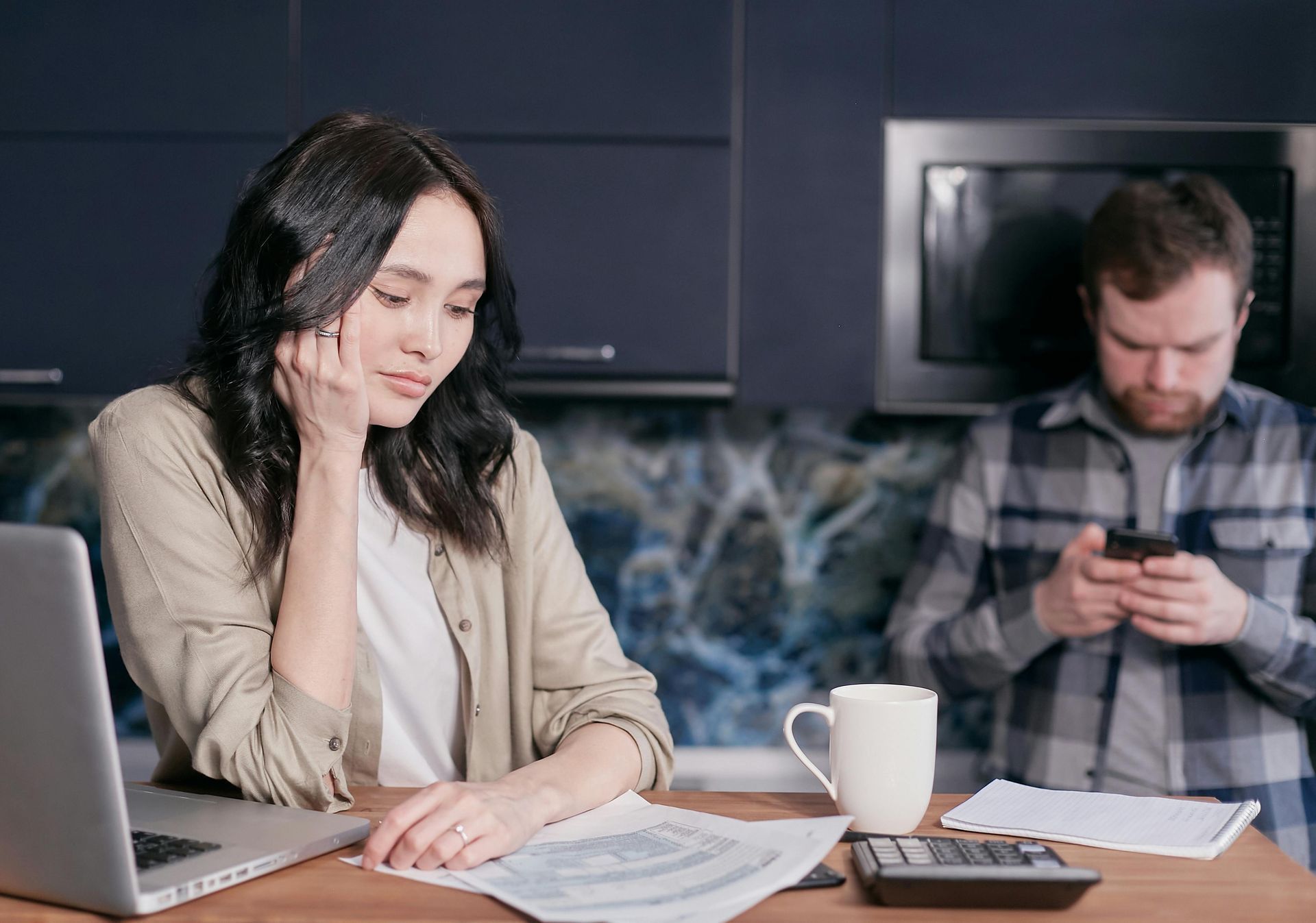 A man checking his phione and a woman reading a document