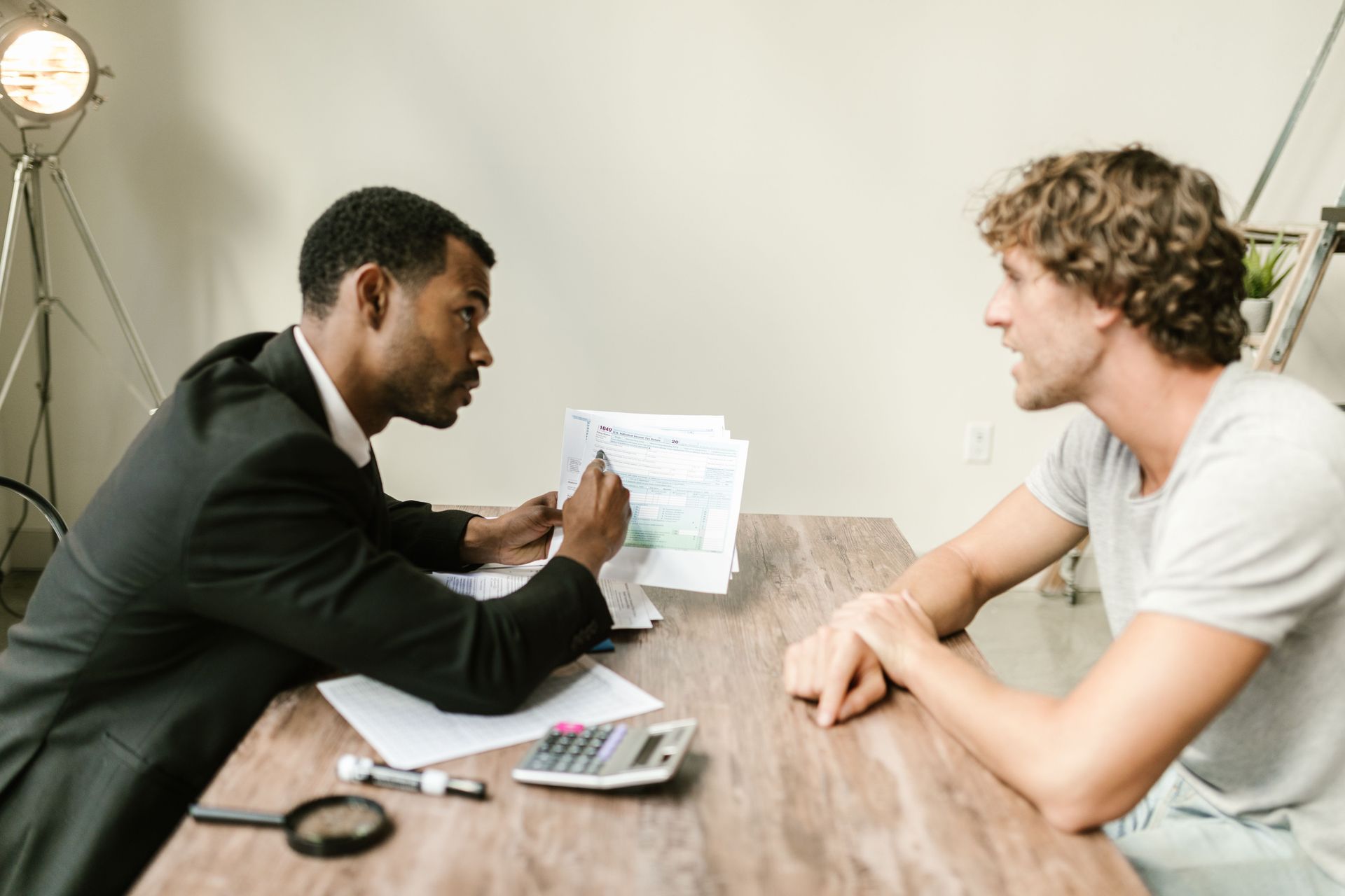 Two people in a meeting at a table, reviewing documents and talking in a bright office