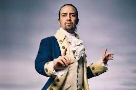 Lin-Manuel Miranda in a military uniform standing in front of a cloudy sky.
