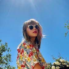 taylor swift is wearing sunglasses and a floral shirt.