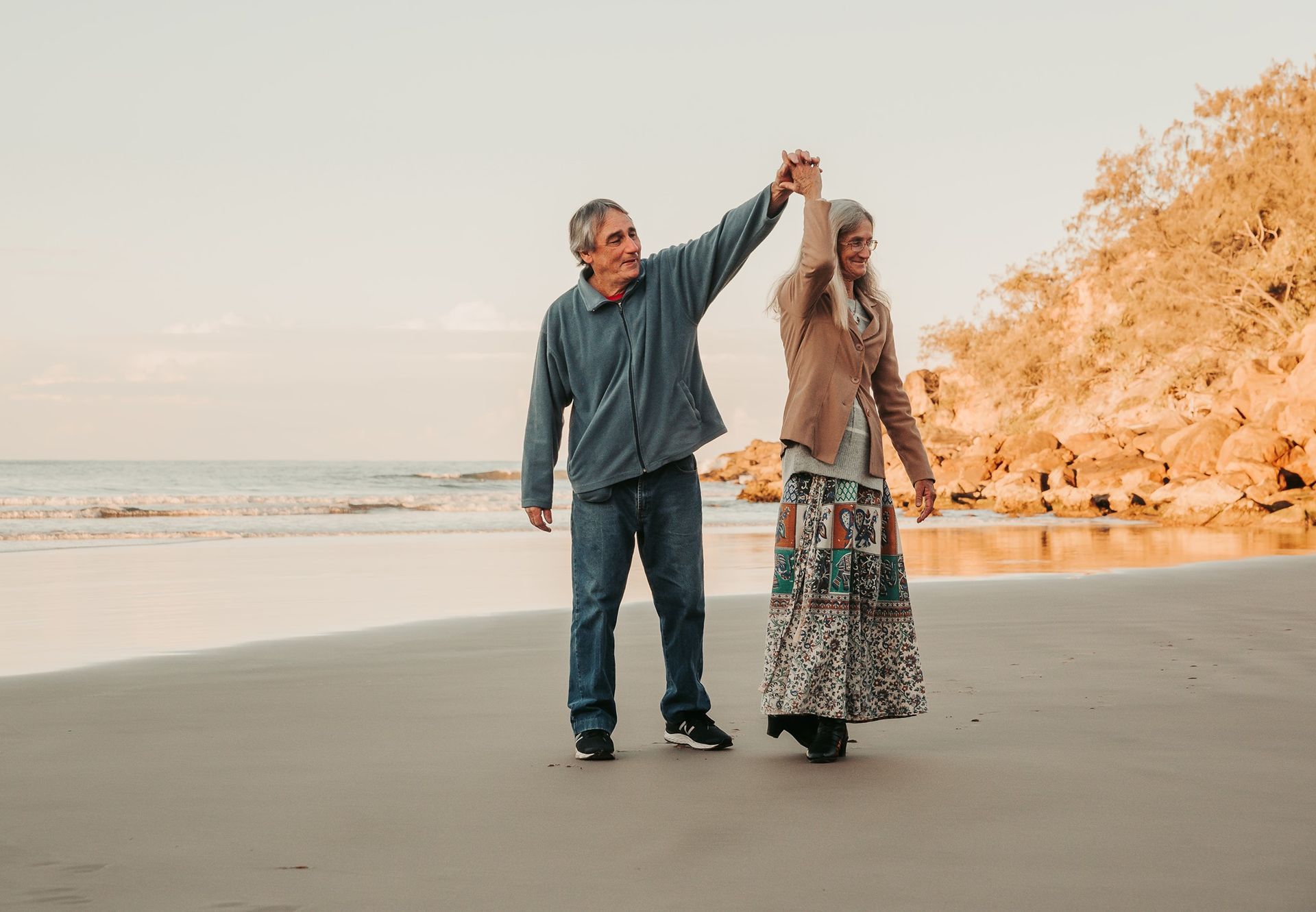 Couple Dances on a Sandy Beach, Man in Blue, Woman in Patterned Skirt — Feathers & Lace Photography in Tarzali, QLD