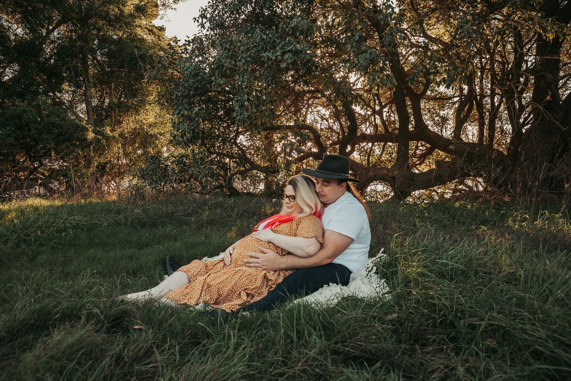 Couple Sitting on a Blanket in Grassy Field, Cuddling — Feathers & Lace Photography in Tarzali, QLD