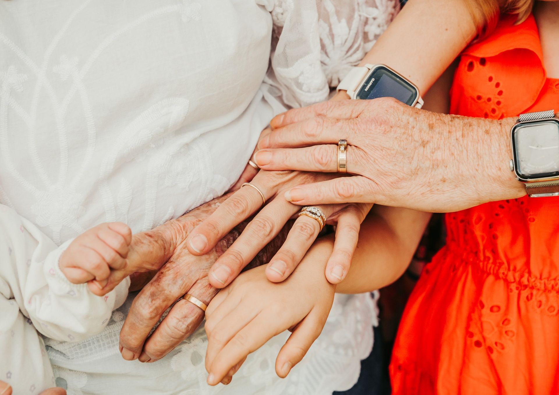 Hands Stacked Together, Wearing Rings, in Front of White Lace and Red Dress — Feathers & Lace Photography in Tarzali, QLD