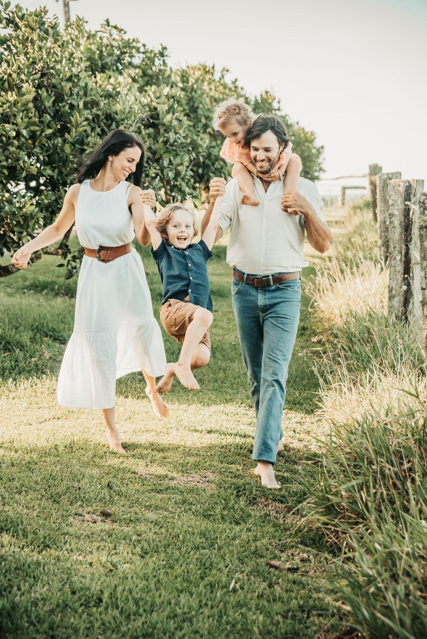 Family Walks Outside; Mom Holds One Child by Hands — Feathers & Lace Photography in Tarzali, QLD