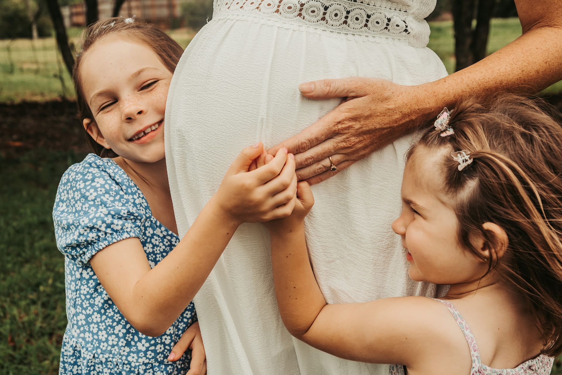 Two Young Girls Touch a Pregnant Woman's Belly, Smiling — Feathers & Lace Photography in Tarzali, QLD