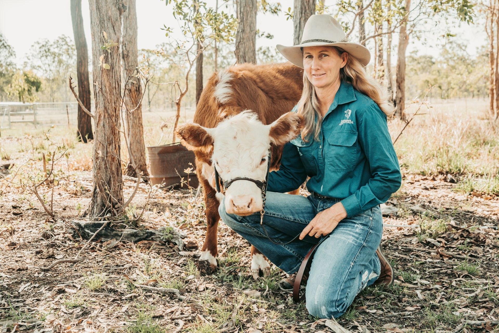 Woman in Cowboy Hat and Work Shirt Kneels Beside a Hereford — Feathers & Lace Photography in Tarzali, QLD