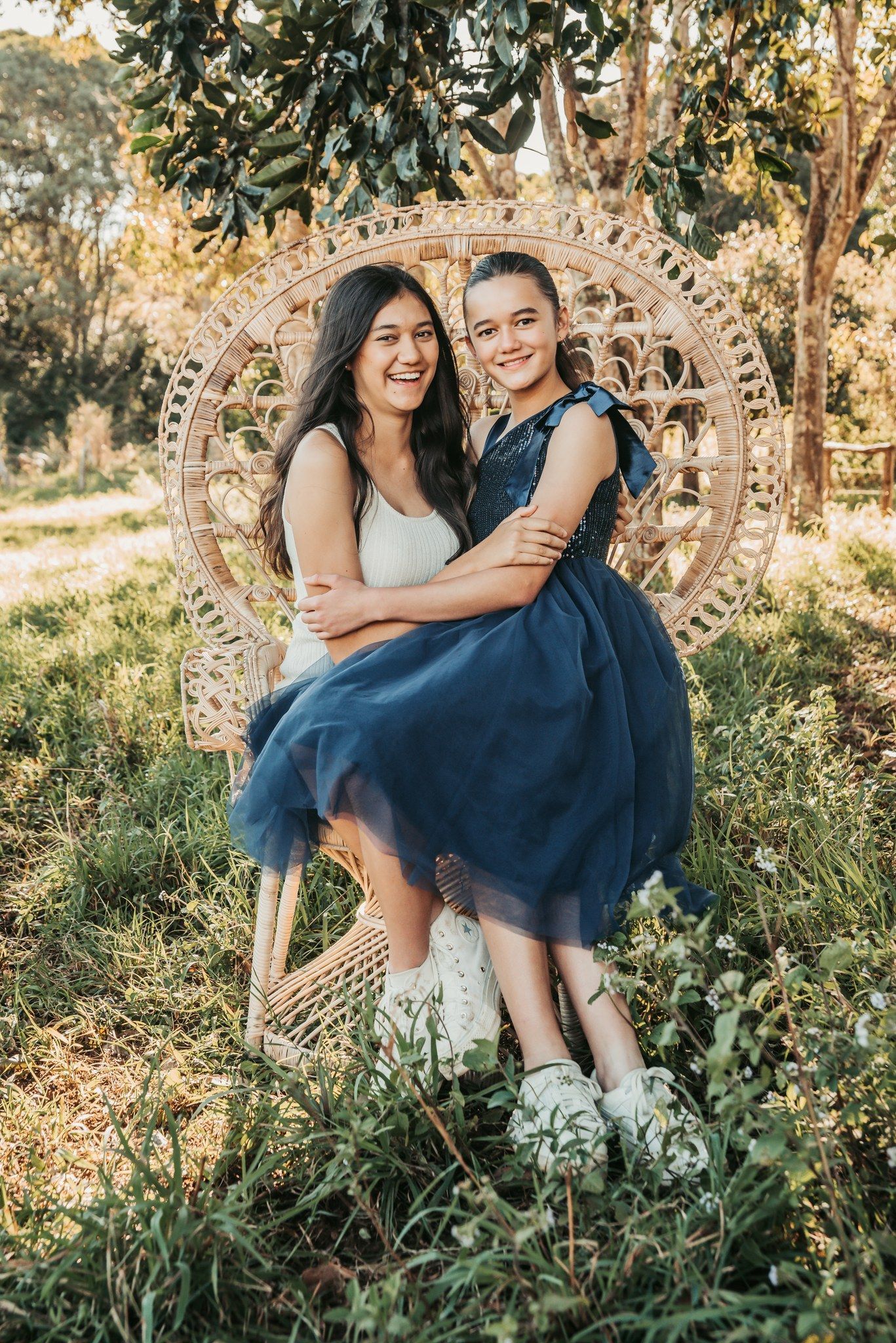 Two Girls Smiling, Embracing in a Woven Chair Outdoor — Feathers & Lace Photography in Tarzali, QLD