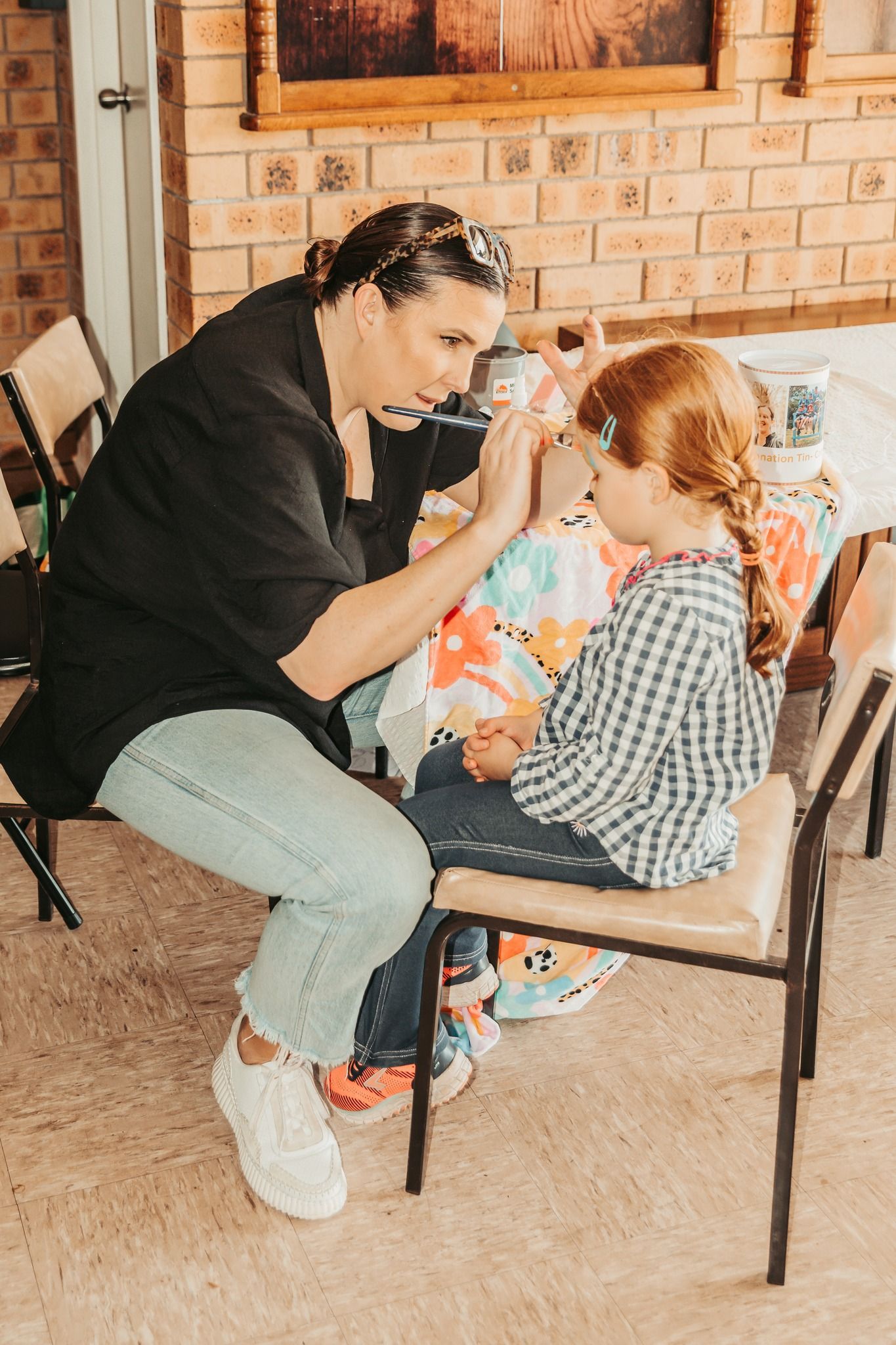 Woman Applying Face Paint to a Child Seated on a Chair Outdoors — Feathers & Lace Photography in Tarzali, QLD