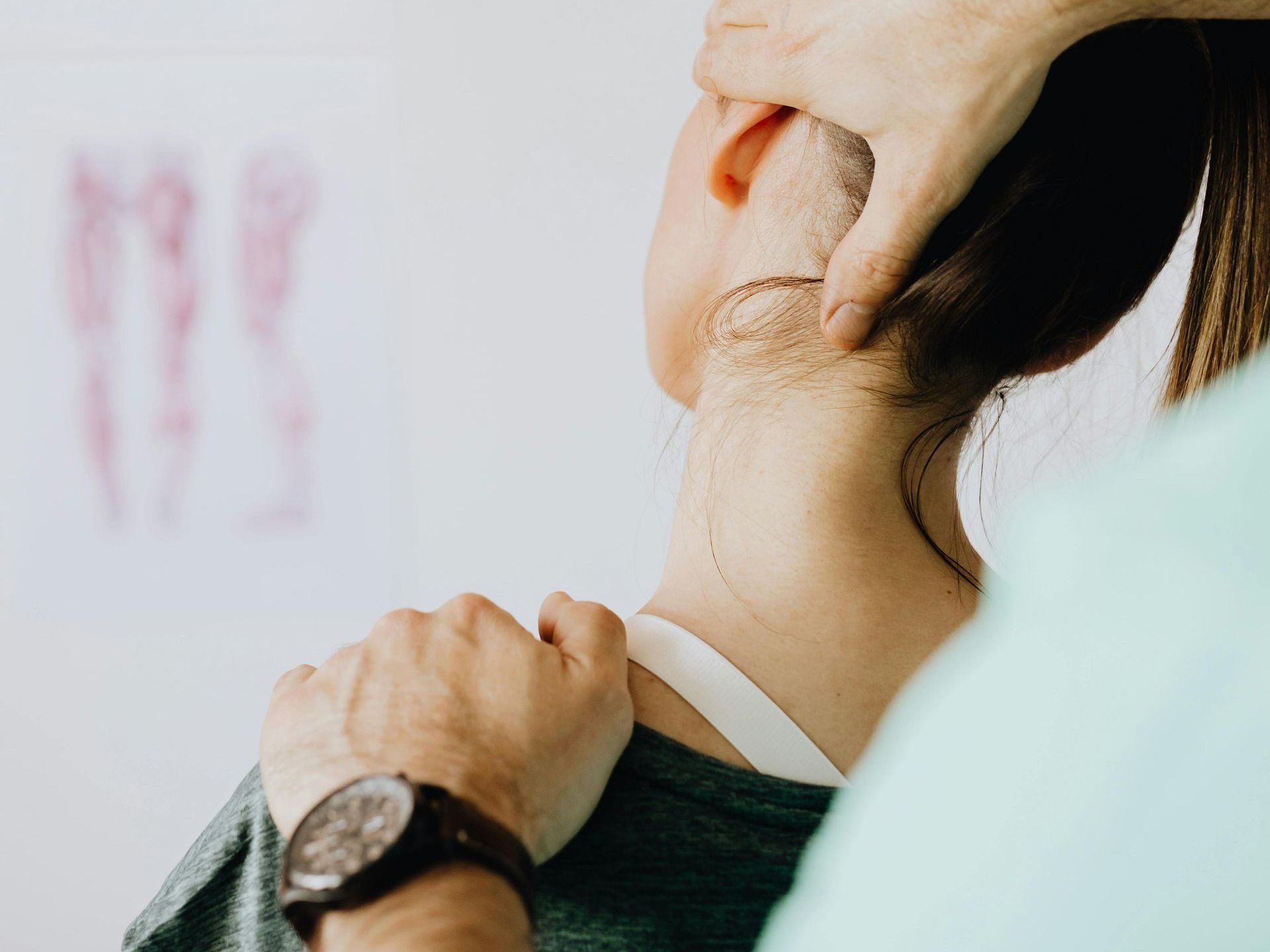 A woman is getting her neck examined by a doctor while wearing a watch.