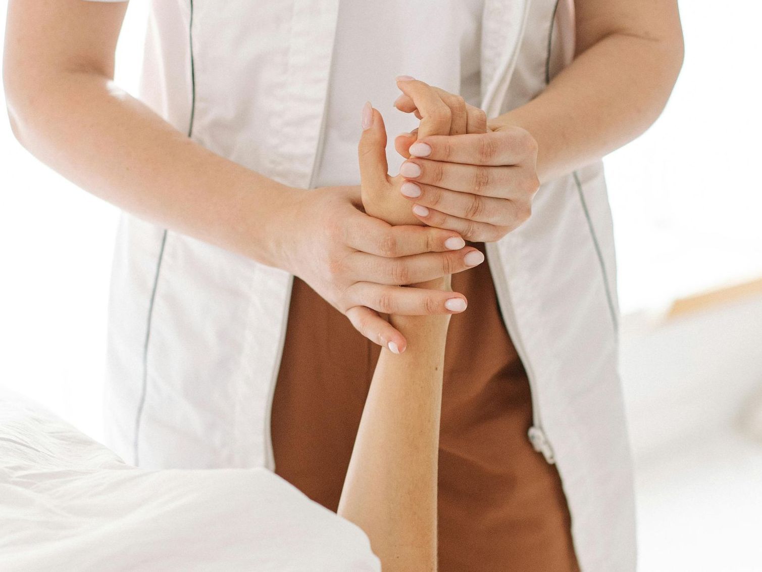 A woman is laying on a bed getting a massage from a woman in a white coat.