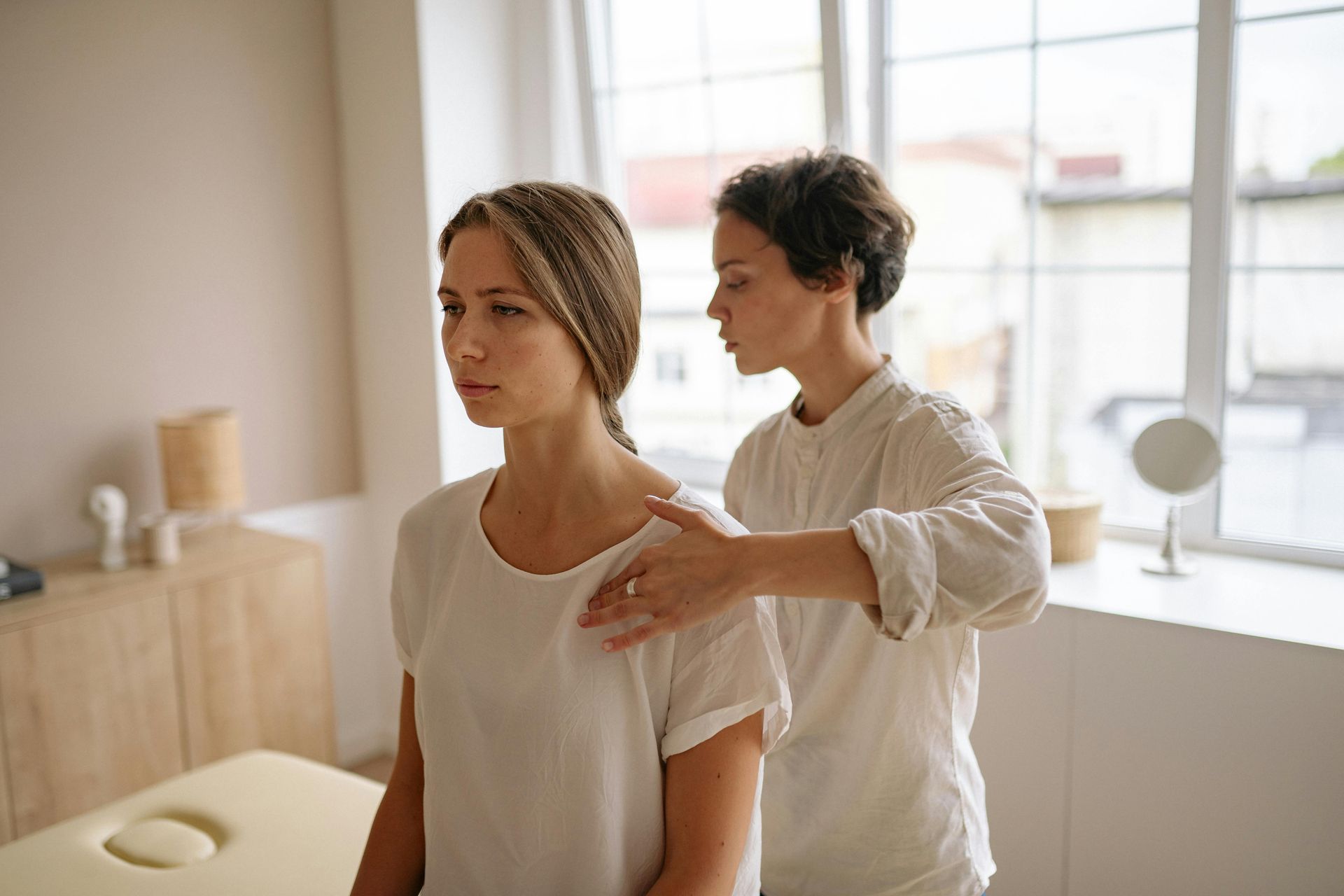 A woman is getting a massage from a woman in a room.