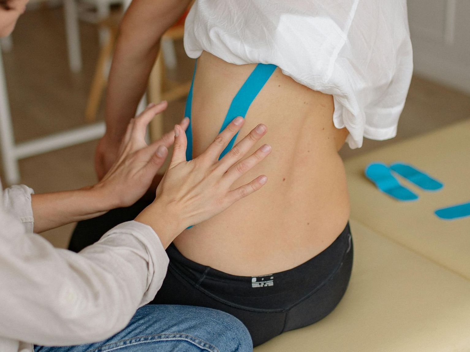 A person is applying kinesio tape to another person 's back.