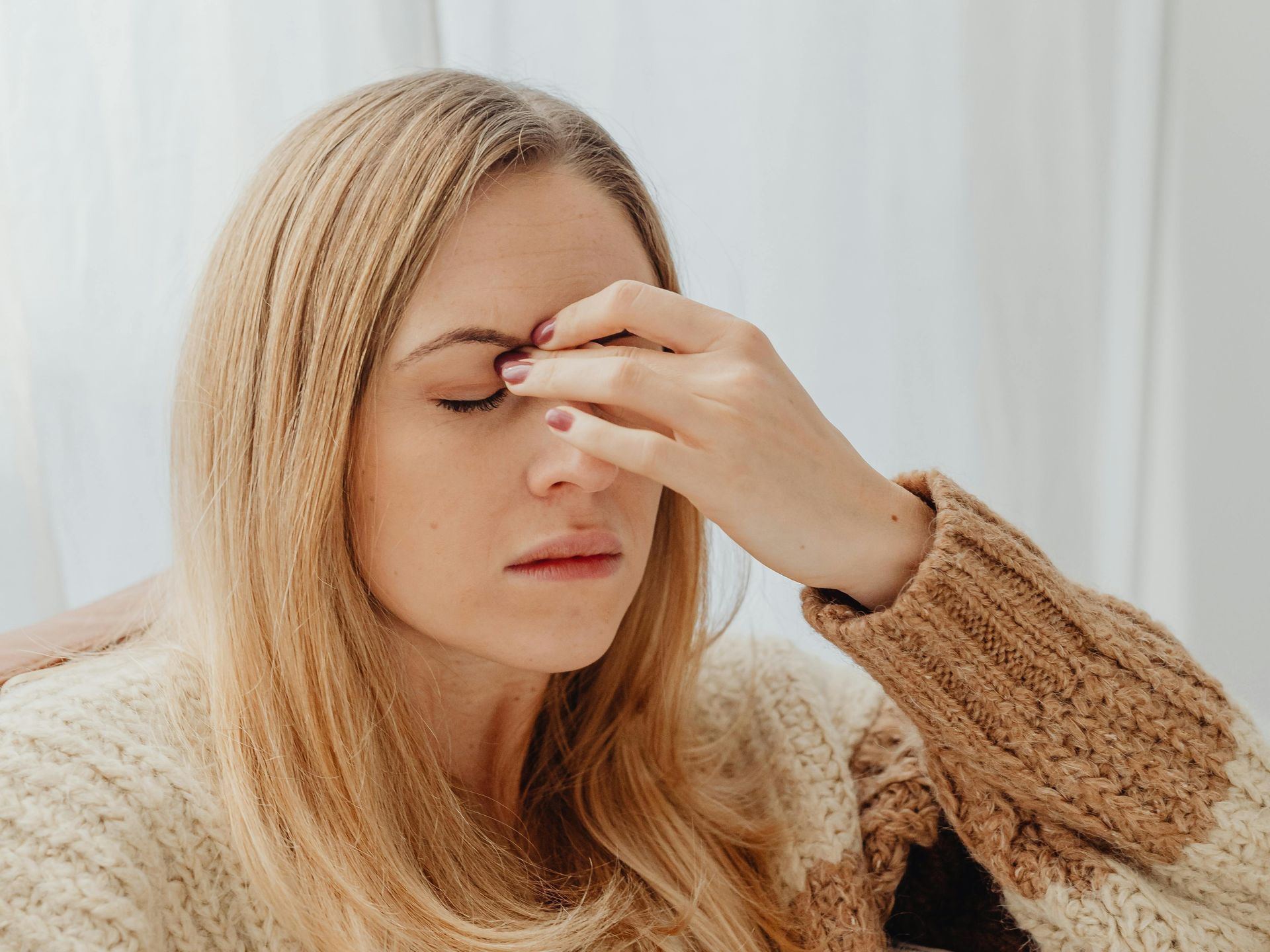 A woman is holding her nose because she has a headache.