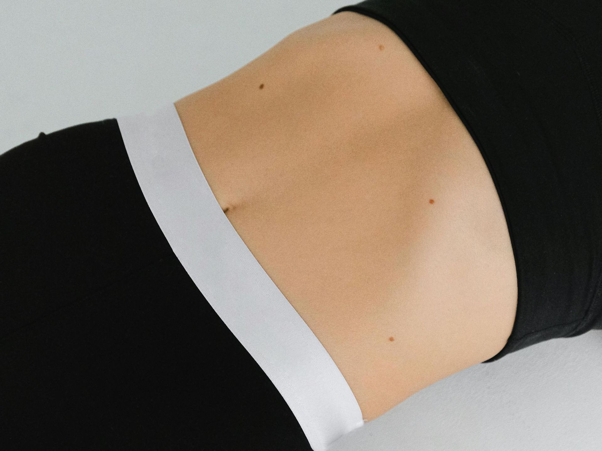 A close up of a woman 's stomach in a black top and black pants