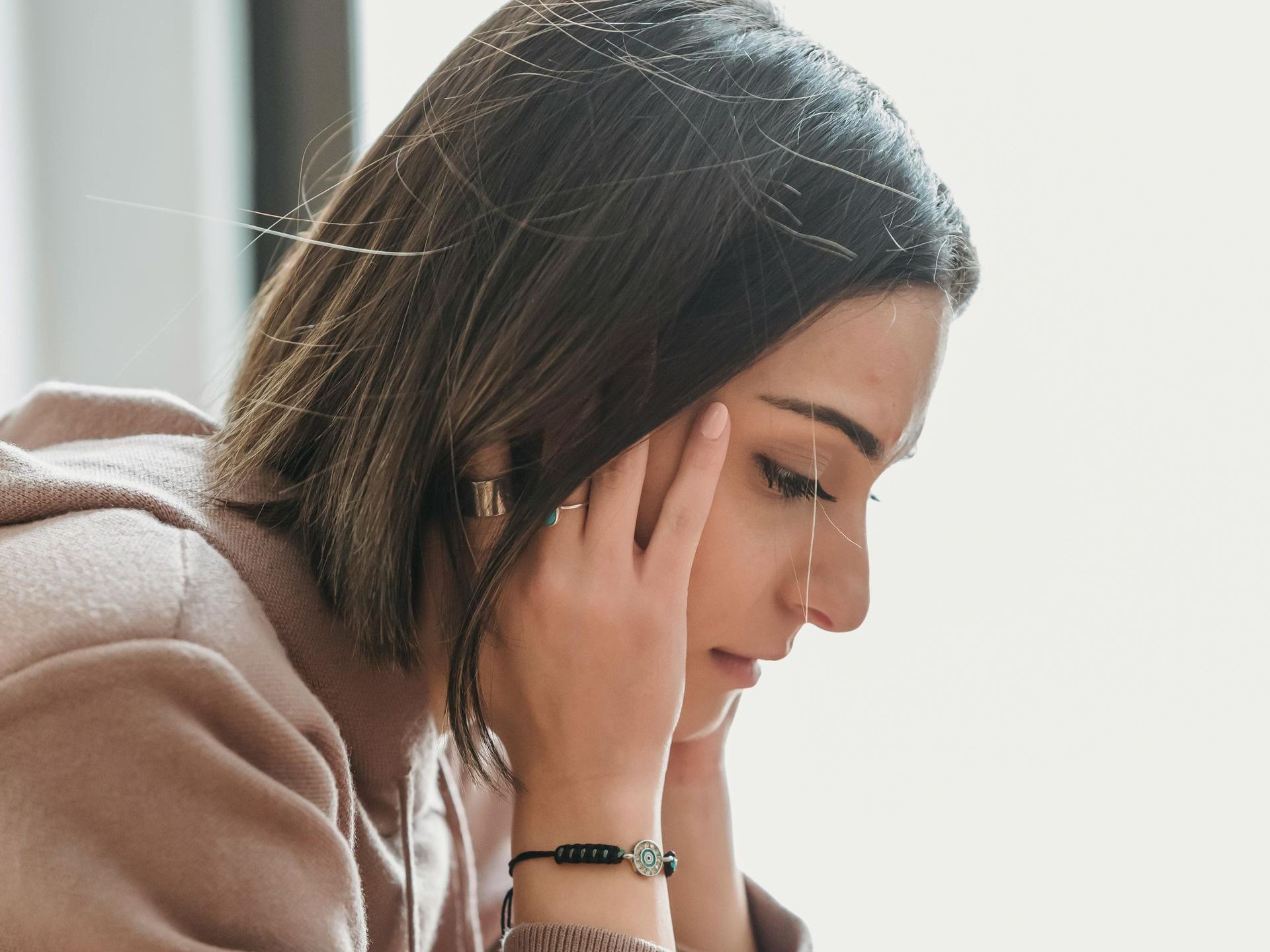 A woman is sitting at a table with her head in her hands.