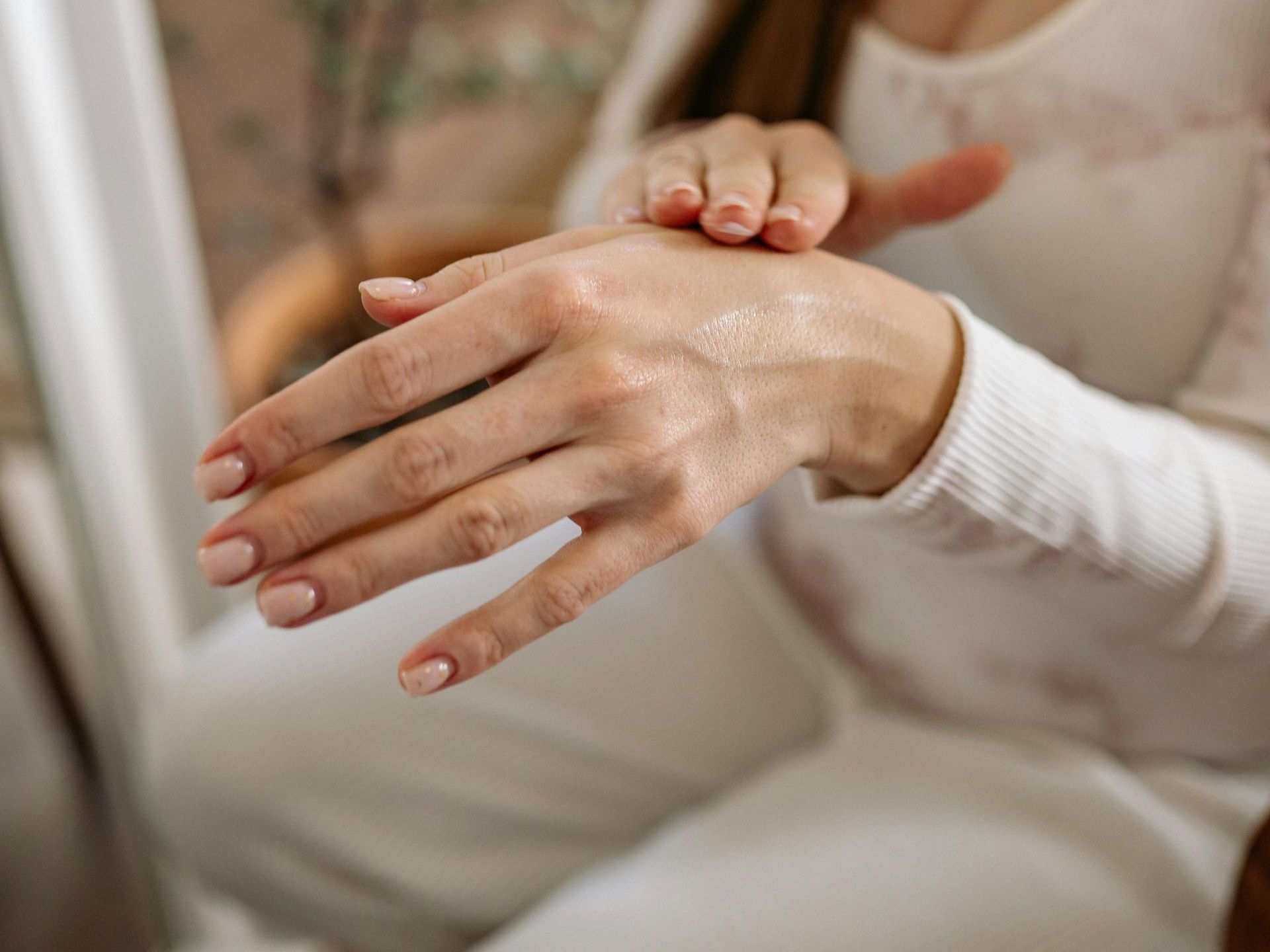 A woman is applying lotion to her hands.