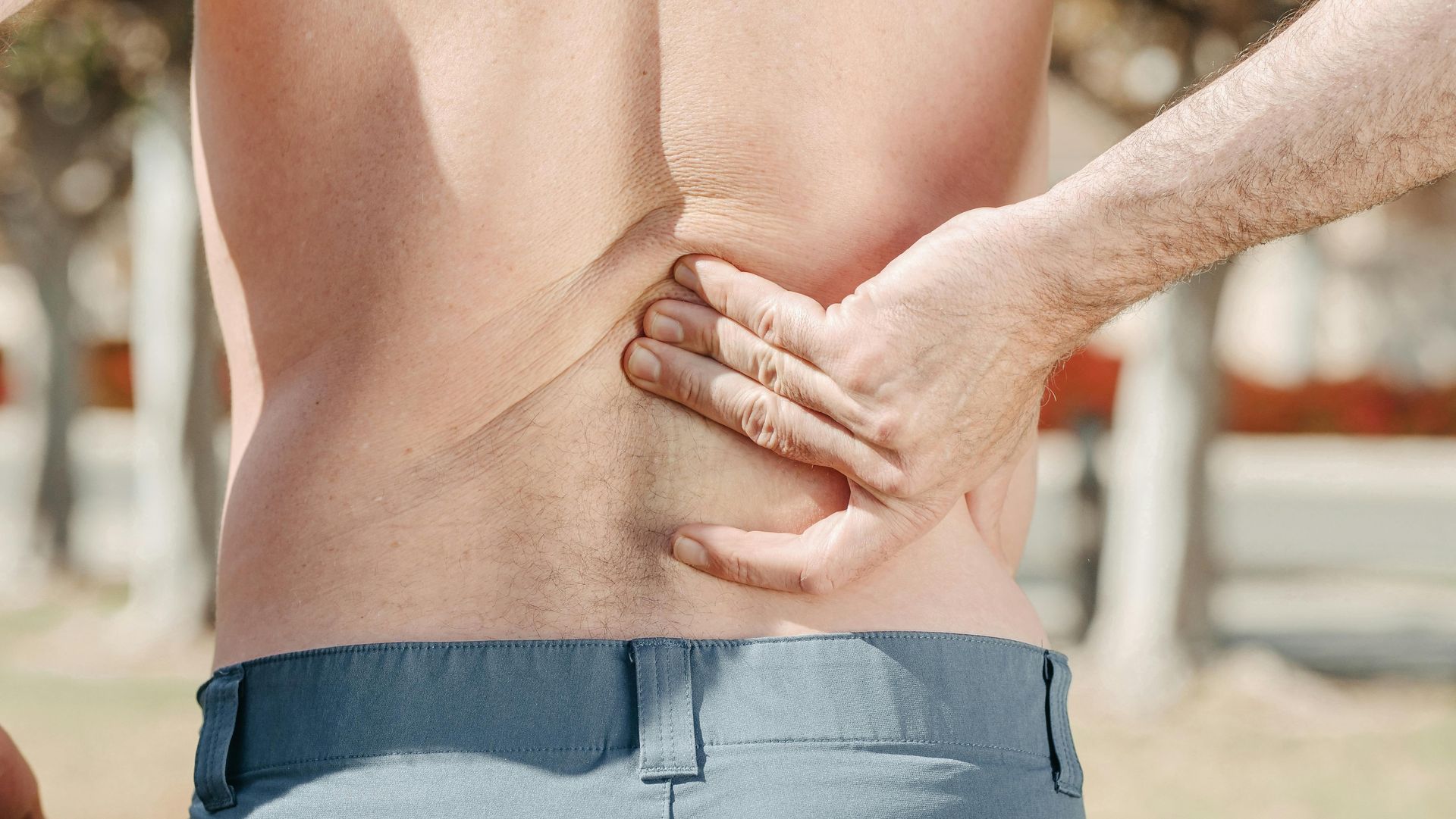A man is holding his back in pain.