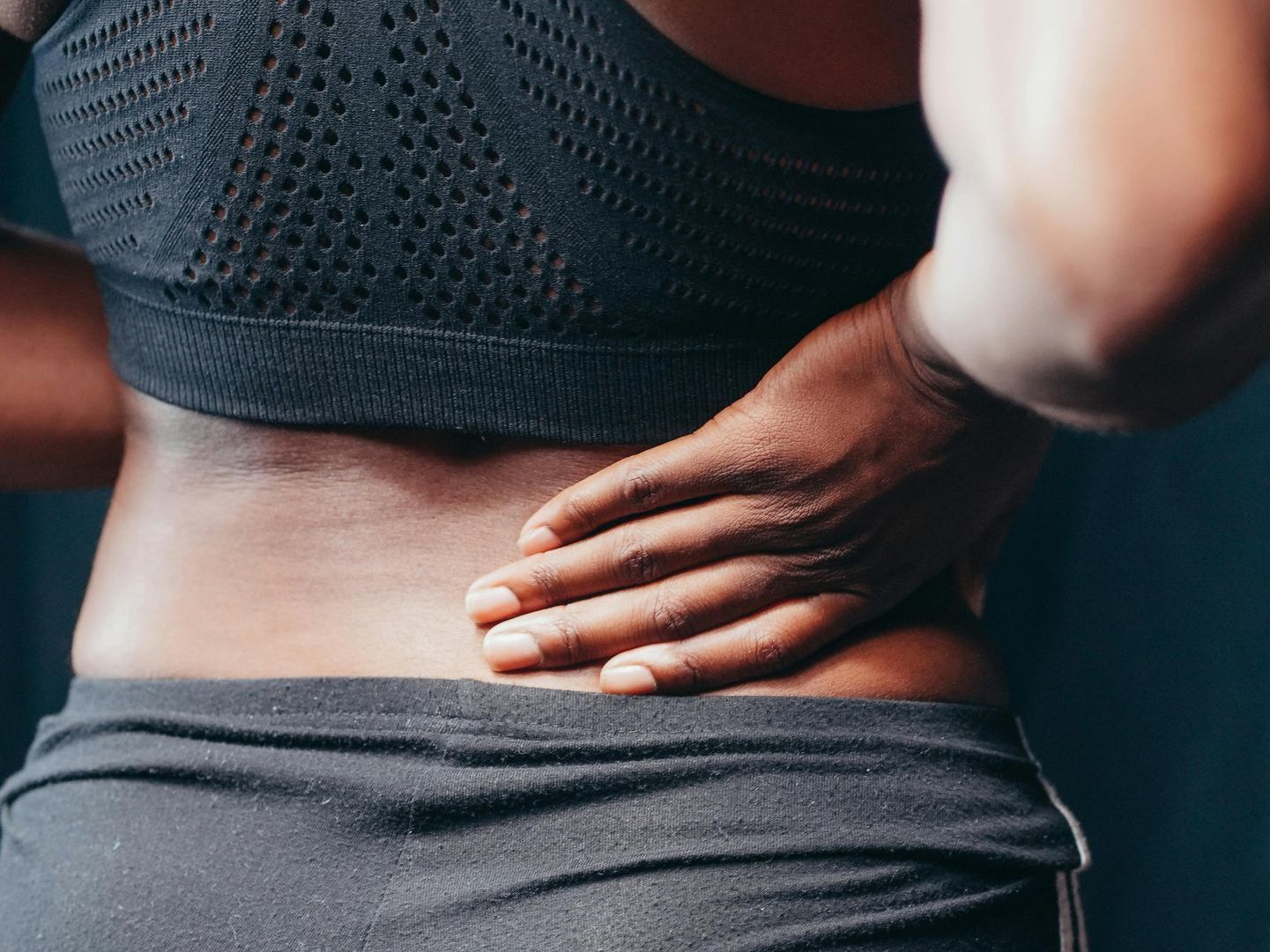 A woman is holding her back in pain.