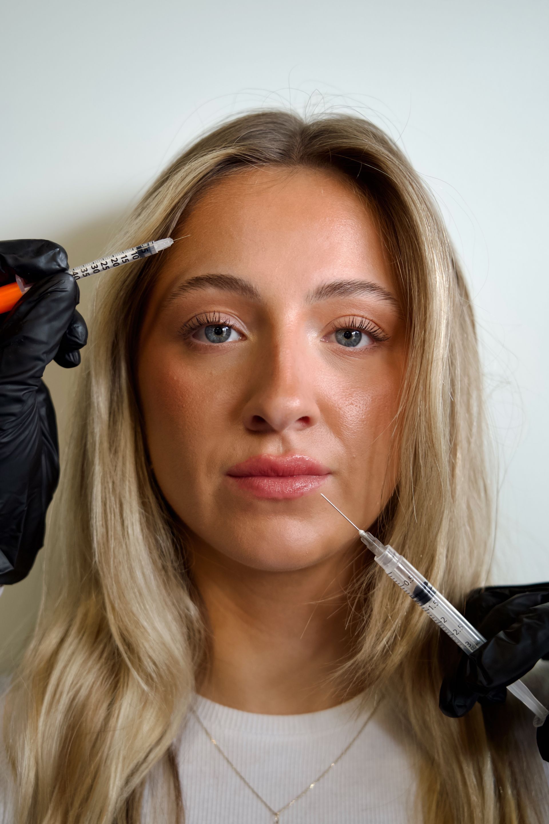 A woman is getting a botox injection in her face.