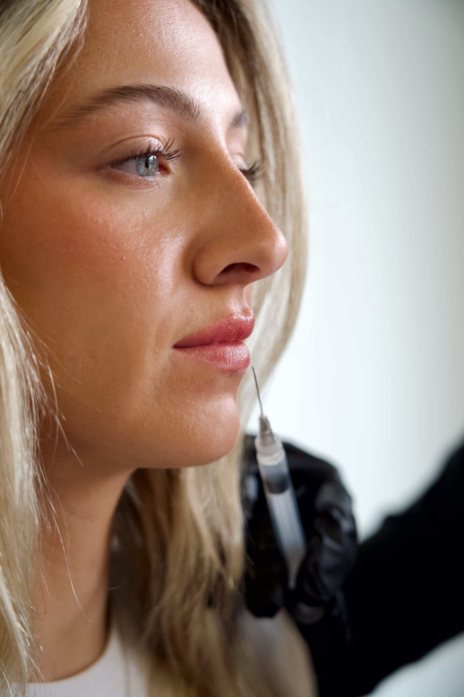 A woman is getting a botox injection in her lips.